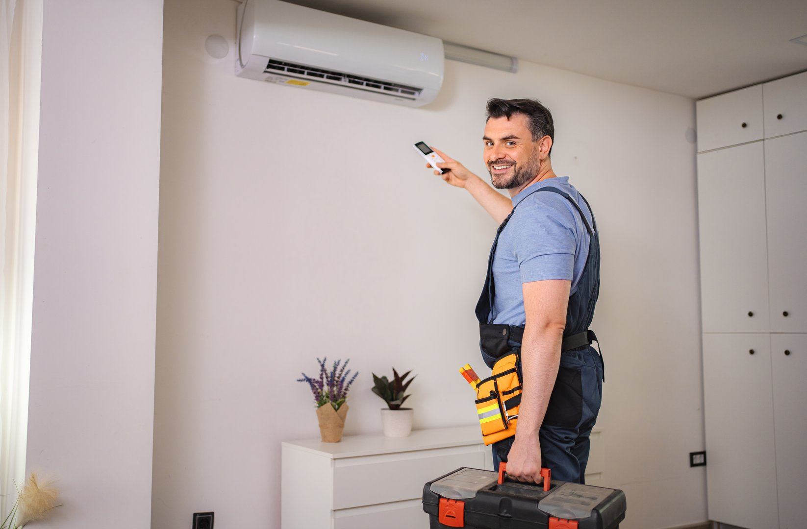 Technician installing an air conditioner and holding a remote control