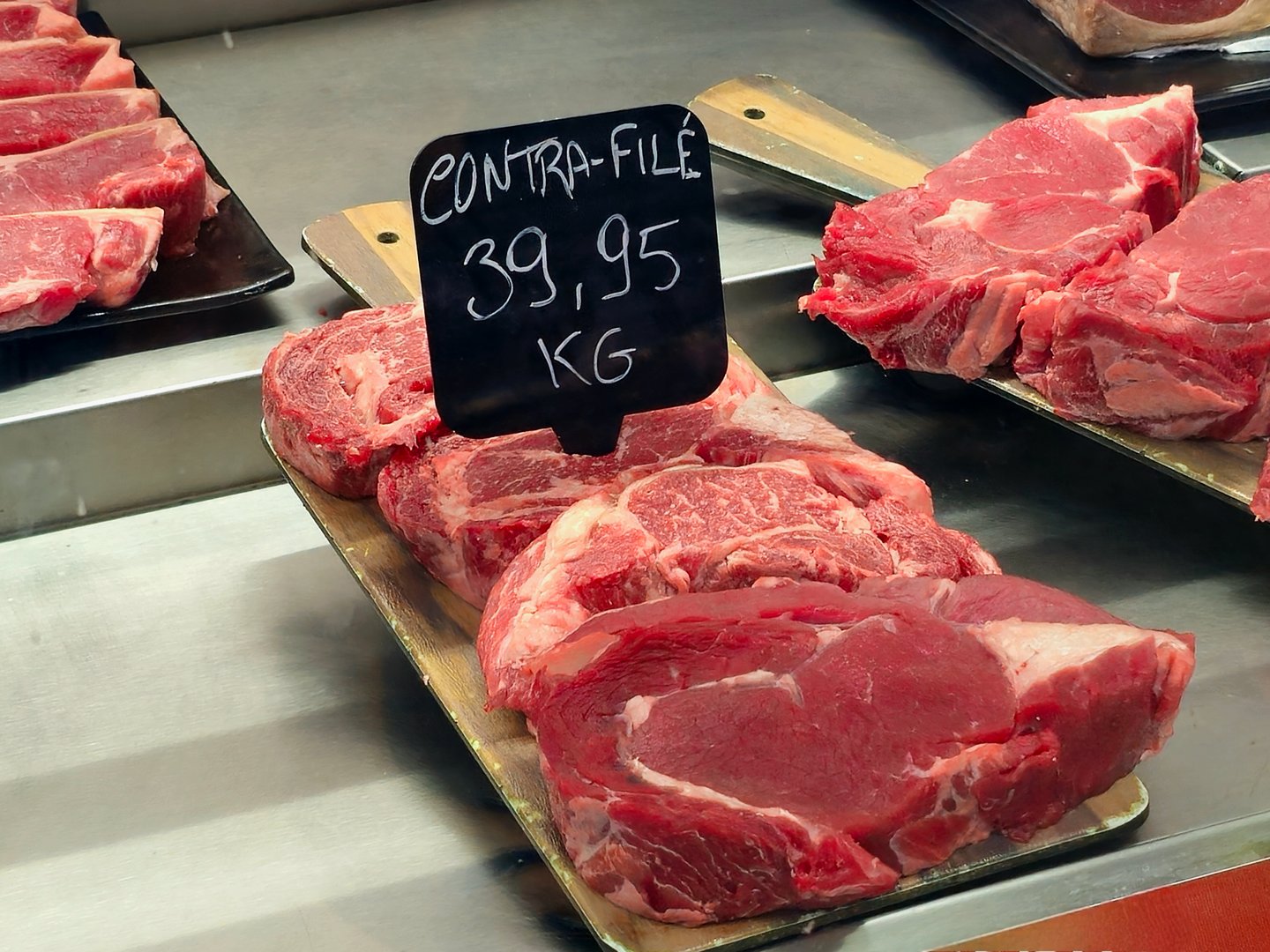 Image showing fresh beef cuts arranged on a metal tray inside a butcher shop or supermarket. The photo highlights the red color, texture, and juicy appearance of the meat, representing quality and freshness in the food industry. Ideal for themes related to food, meat trade, gastronomy, and fresh product consumption.