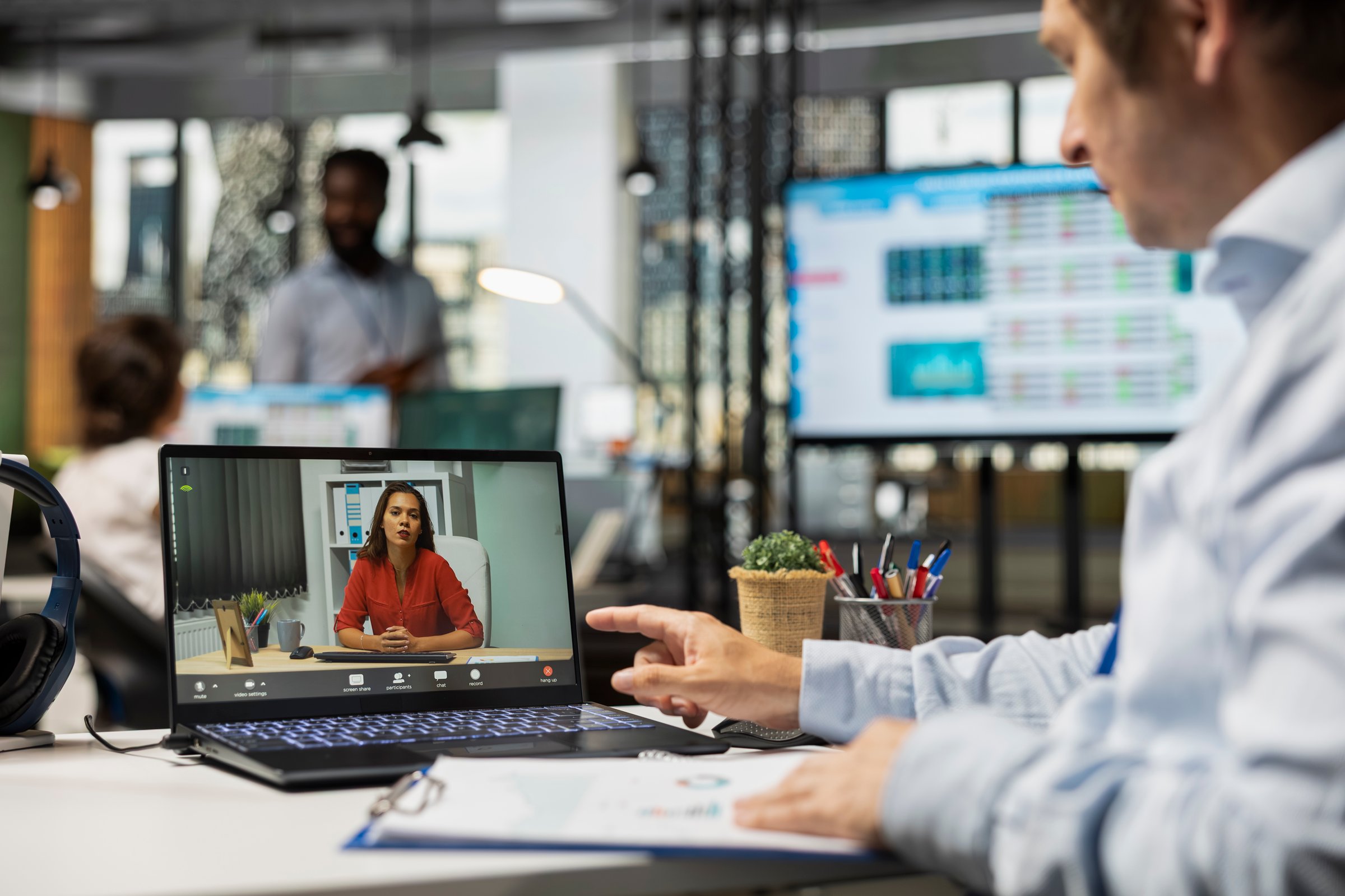 Male corporate employee with clipboard conducts virtual business evaluations and negotiations with professional woman. Company manager on video call discussing with remote female coworker.