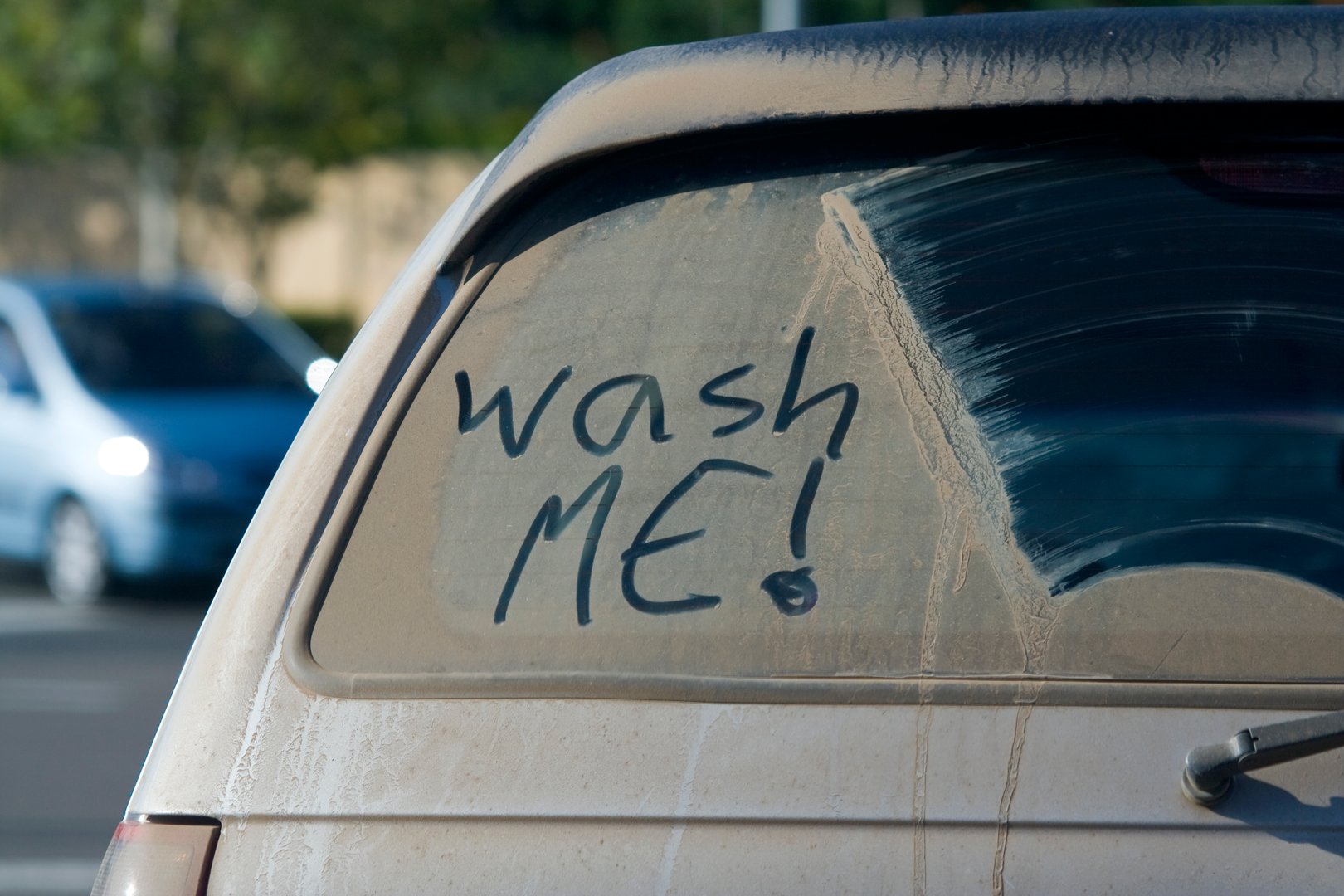Dirty car window and wash me sign. Shallow depth of the field.