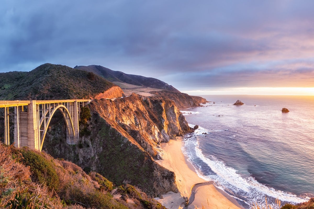 Scenic view of Bixby Creek Bridge and coastal cliffs at sunset in Big Sur, California.