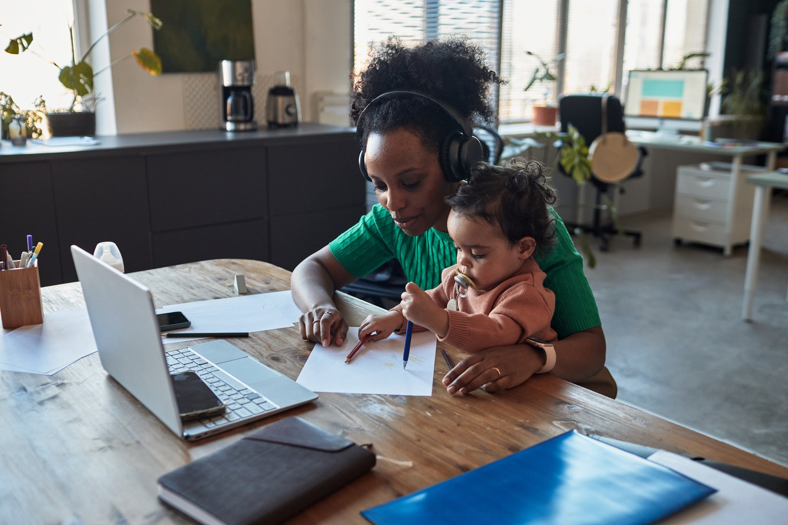 Busy mother working from home while multitasking childcare in a modern office space setting, highlighting the balance between work and family life