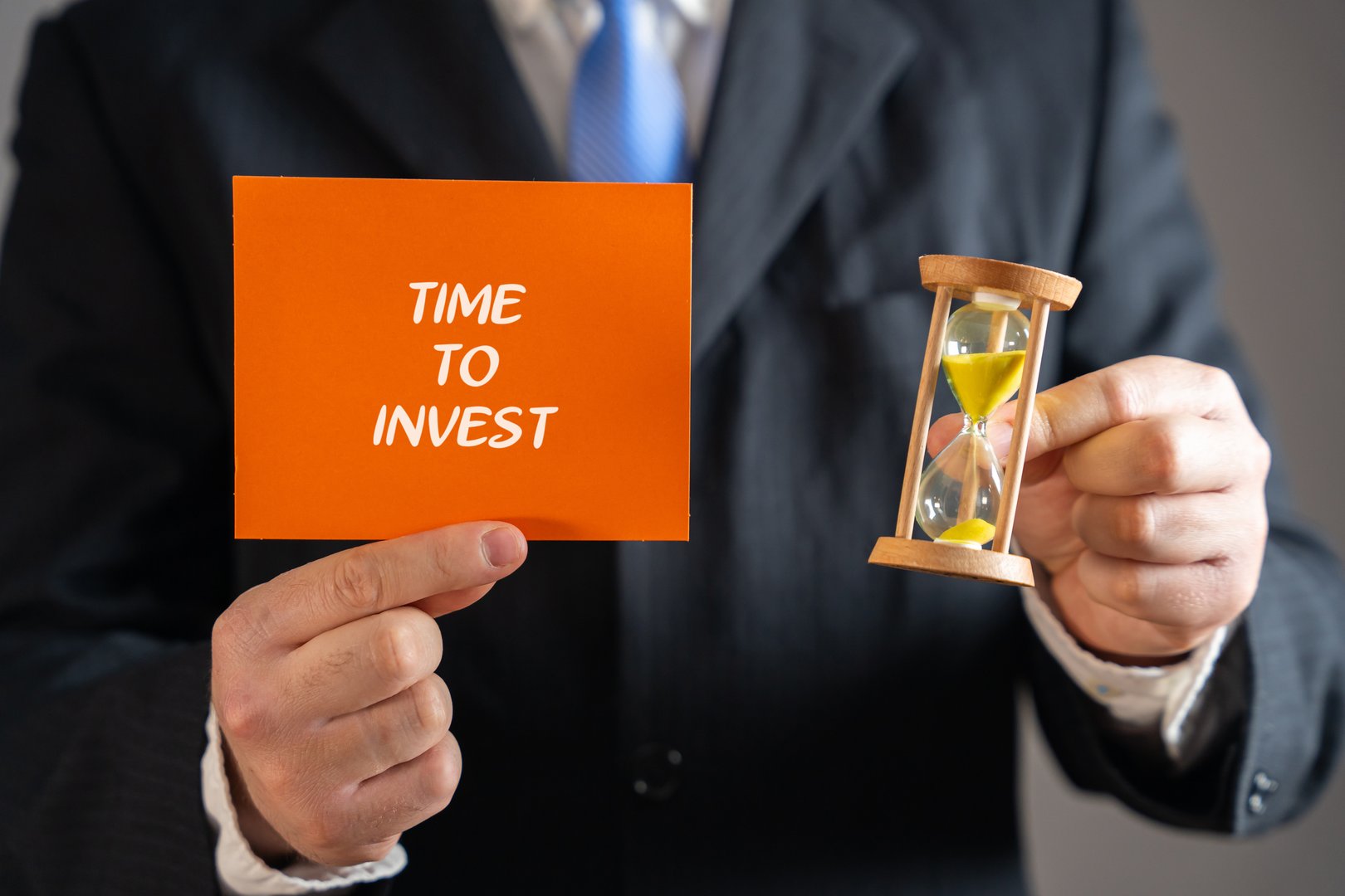Time to invest notes in hand businessman. Right moment to put money, effort, or resources into a business opportunity. Note with words and hourglass