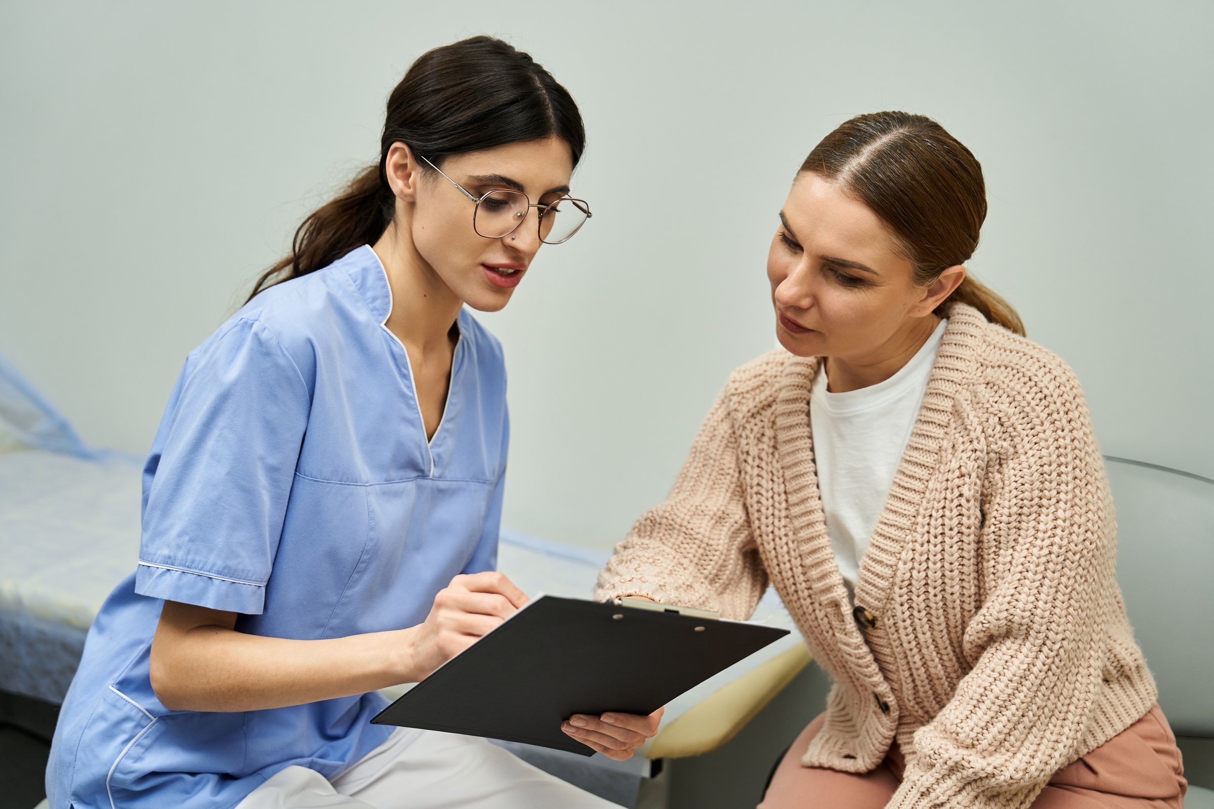 A professional gynecologist discusses health concerns with a patient in a contemporary clinic.
