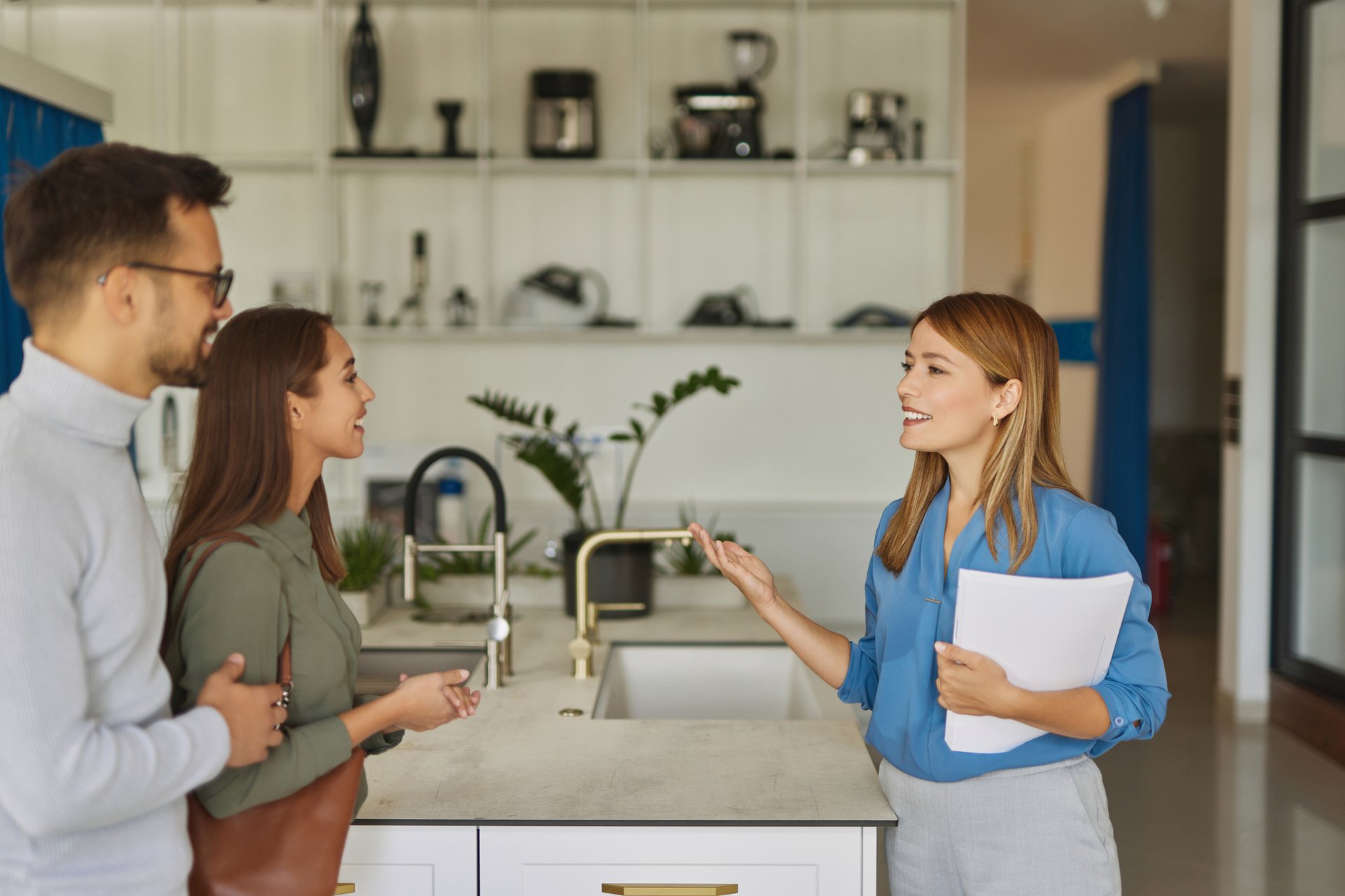 Female shop assistant helping young couple choose new kitchen faucet - sugarfree.space healthy family planning