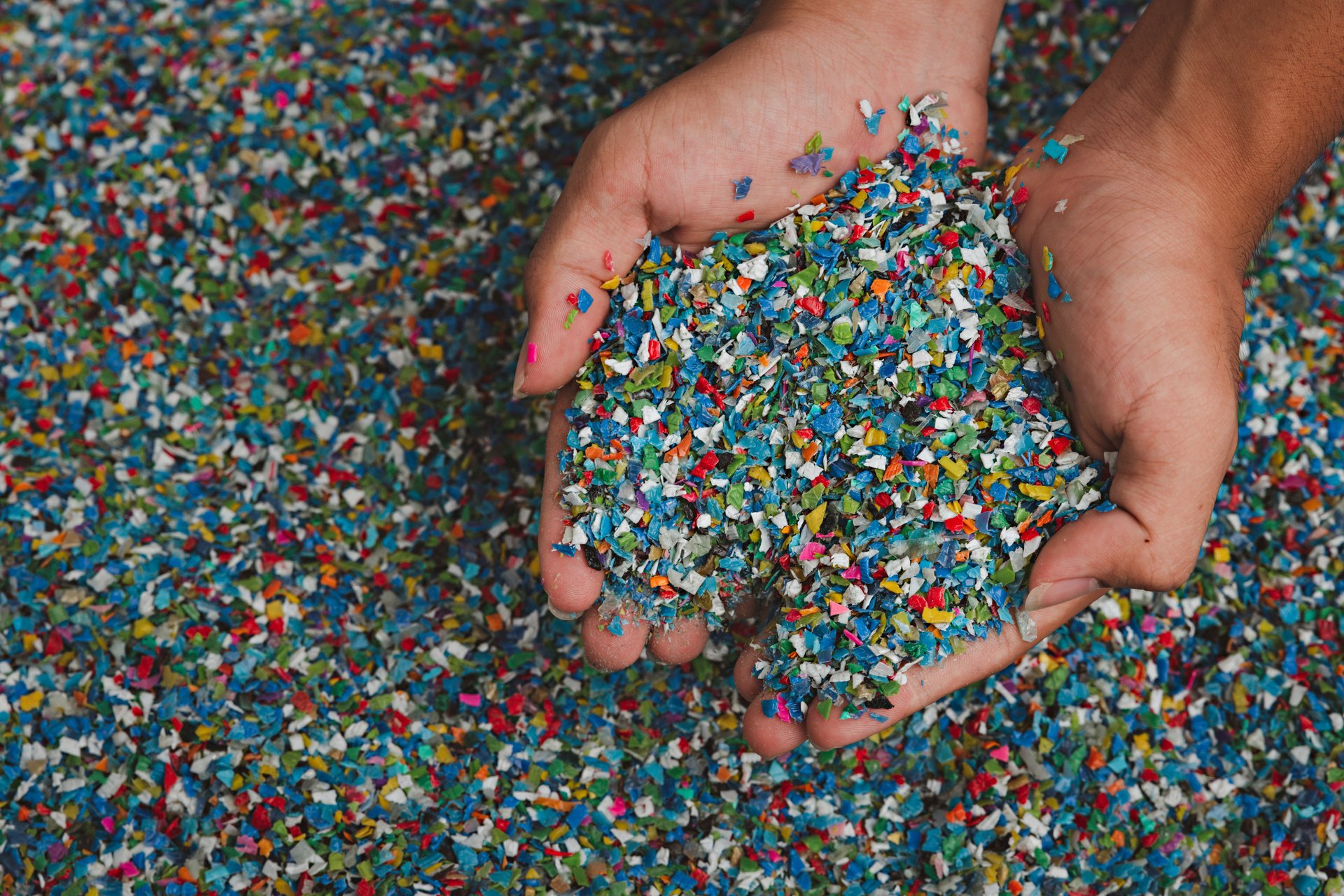 Hands hold clear white plastic pellets, raw materials for various manufacturing processes. These pellets are widely used in industries to produce products like packaging, bottles, and equipment parts. The white background highlights the pellets, making them stand out.