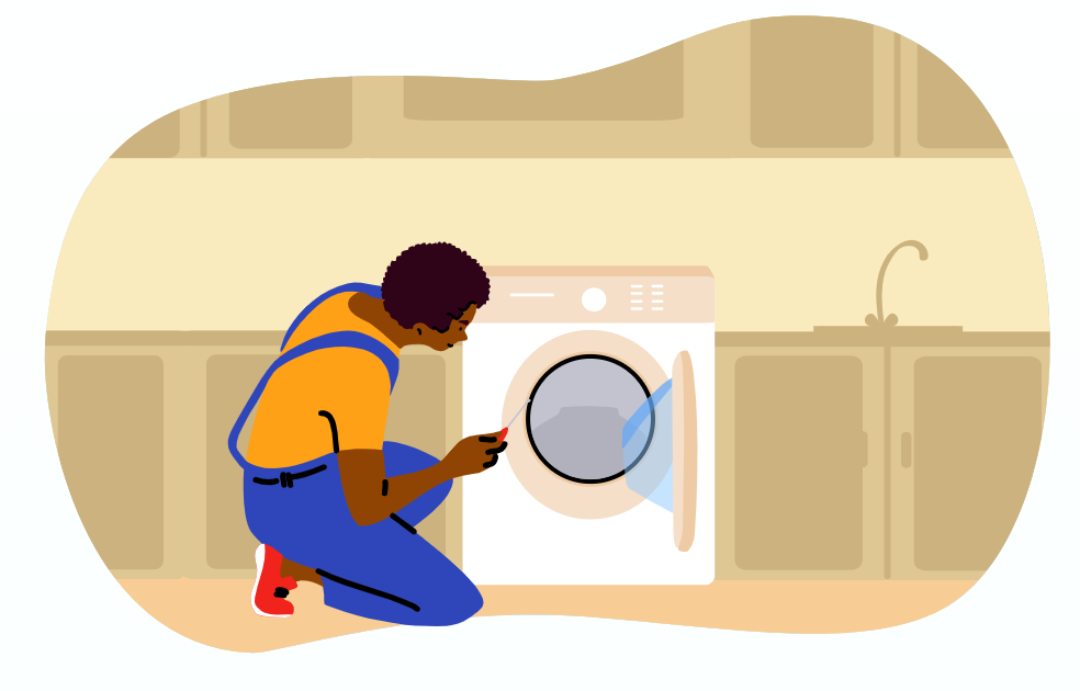 Person in overalls kneeling and repairing a washing machine in a kitchen setting.
