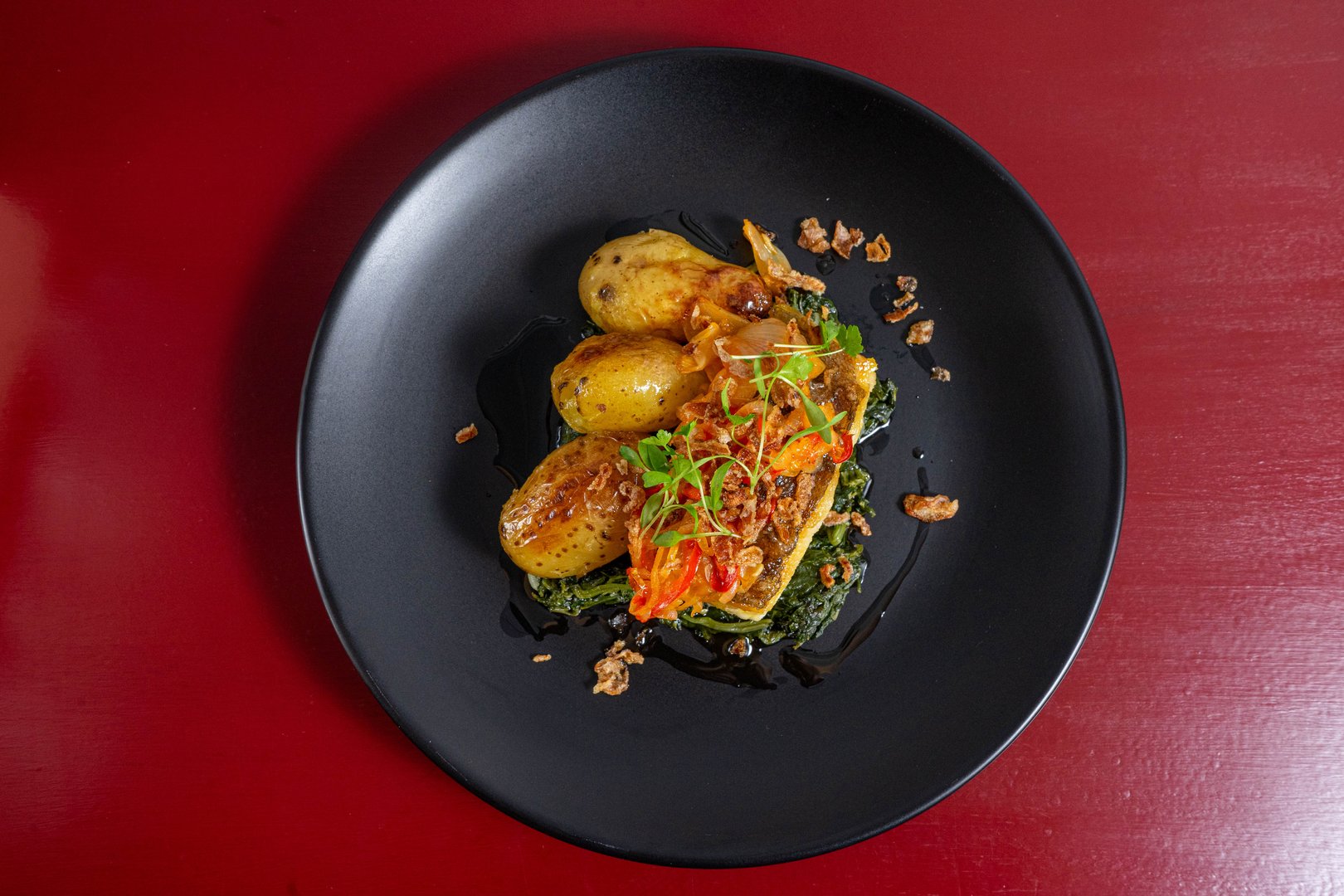 Grilled cod 'à lagareiro' on a bed of Portuguese spinach puree, crafted by a top chef, showcasing traditional flavors and gourmet presentation.