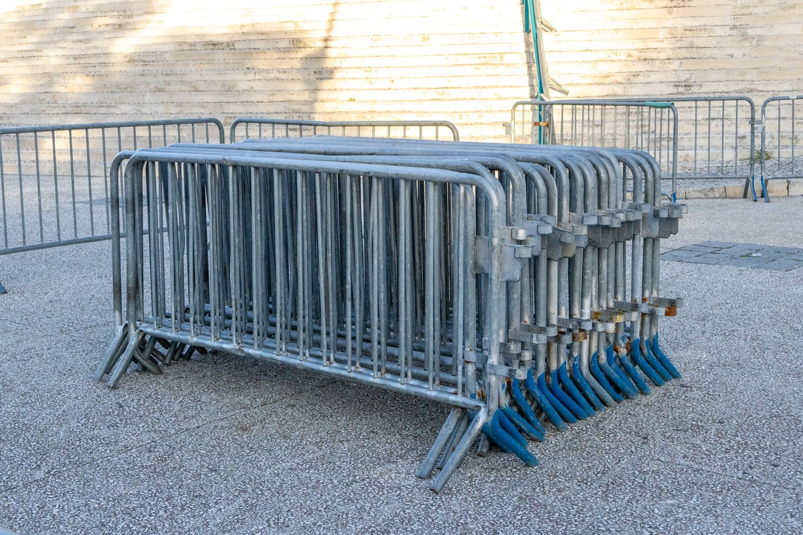 Galvanized steel crowd control barriers stacked together, ready for deployment in a public space