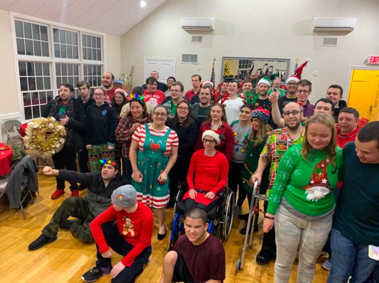 Group of people celebrating a holiday, wearing festive outfits and accessories, indoors with holiday decorations.