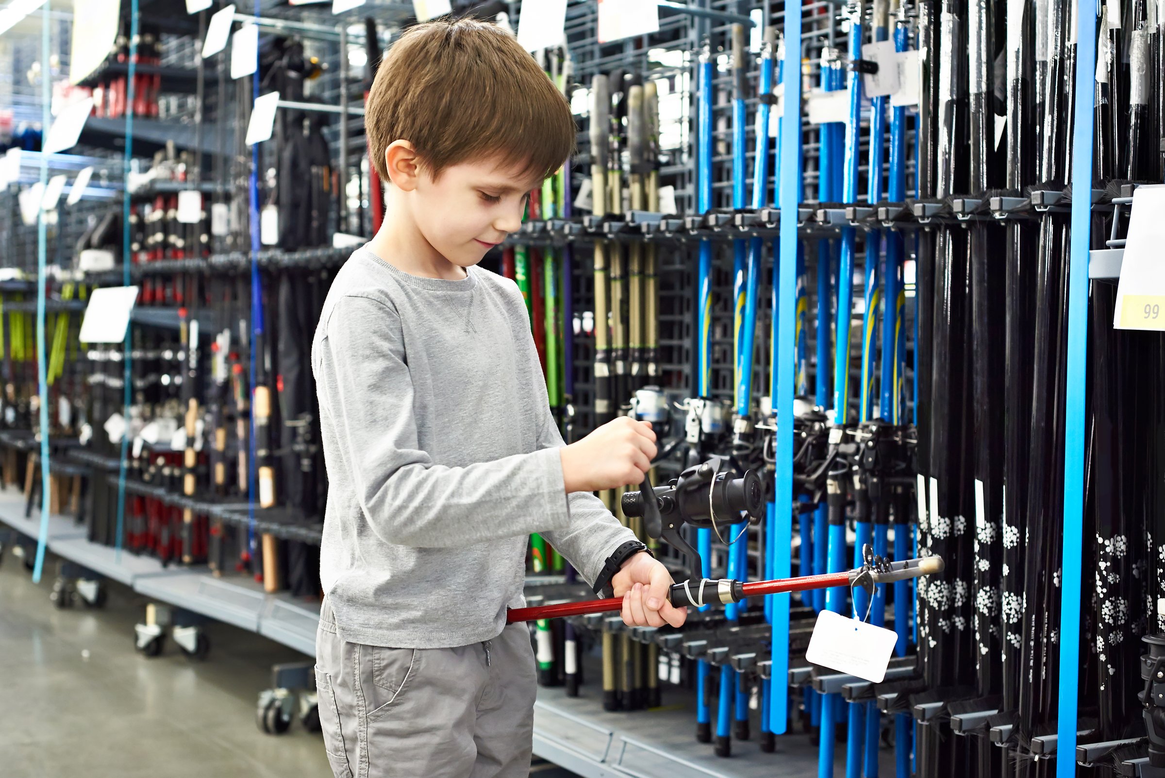 Boy with a fishing rod in a sports shop