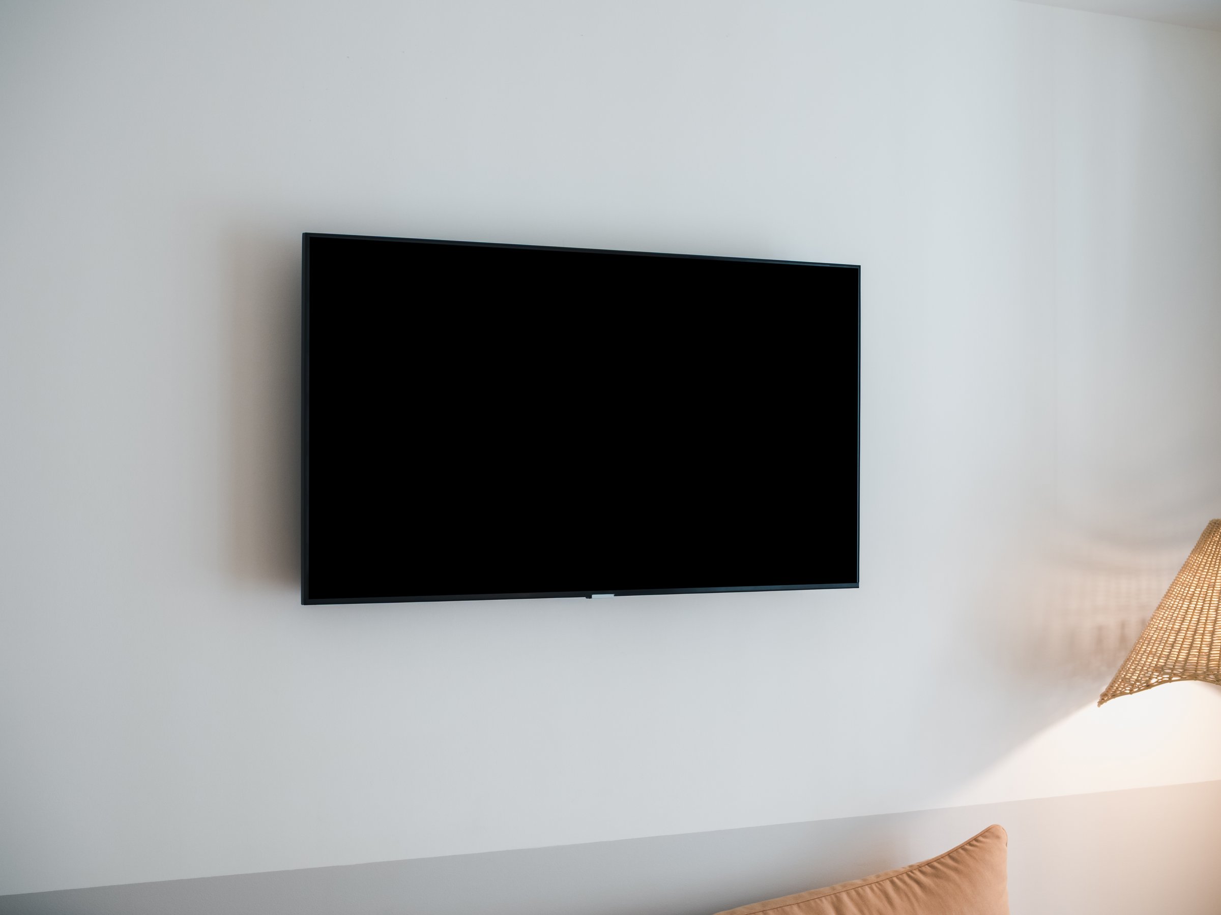 Black blank space on LED smart TV with dark empty screen mounted on white wall background in the guest hotel room. Scene of television with rectangle square space display.