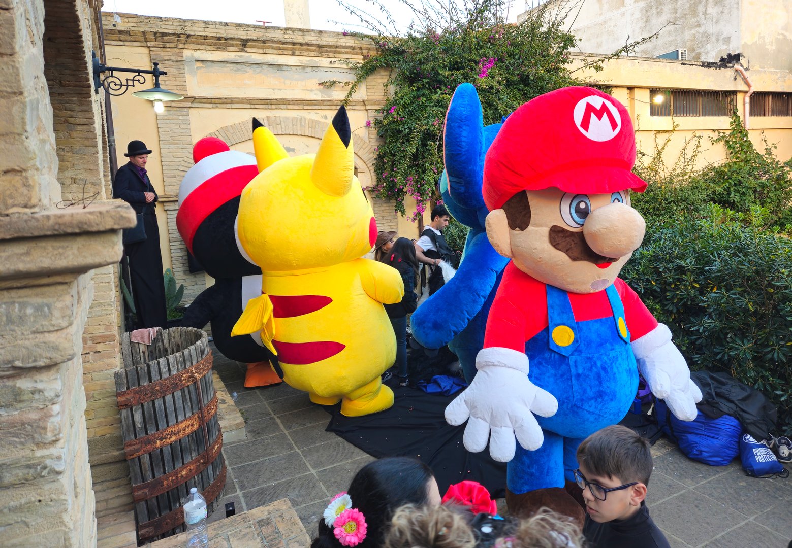 Maracalagonis, Sardinia, Italy, March 2, 2025. For the city Carnival, a big party with allegorical floats, themed groups and masks. For children and adults, the Municipality and the Proloco have also planned an animation with 3-meter-high Puppets depicting, among other things, Pikachu Super Mario, Penguin and a stilt walker. In front some curious while in the background you can see the stilt walker and some operators getting ready.