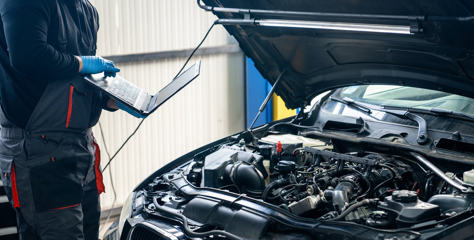 Serviceman with laptop checks car software in car service.
