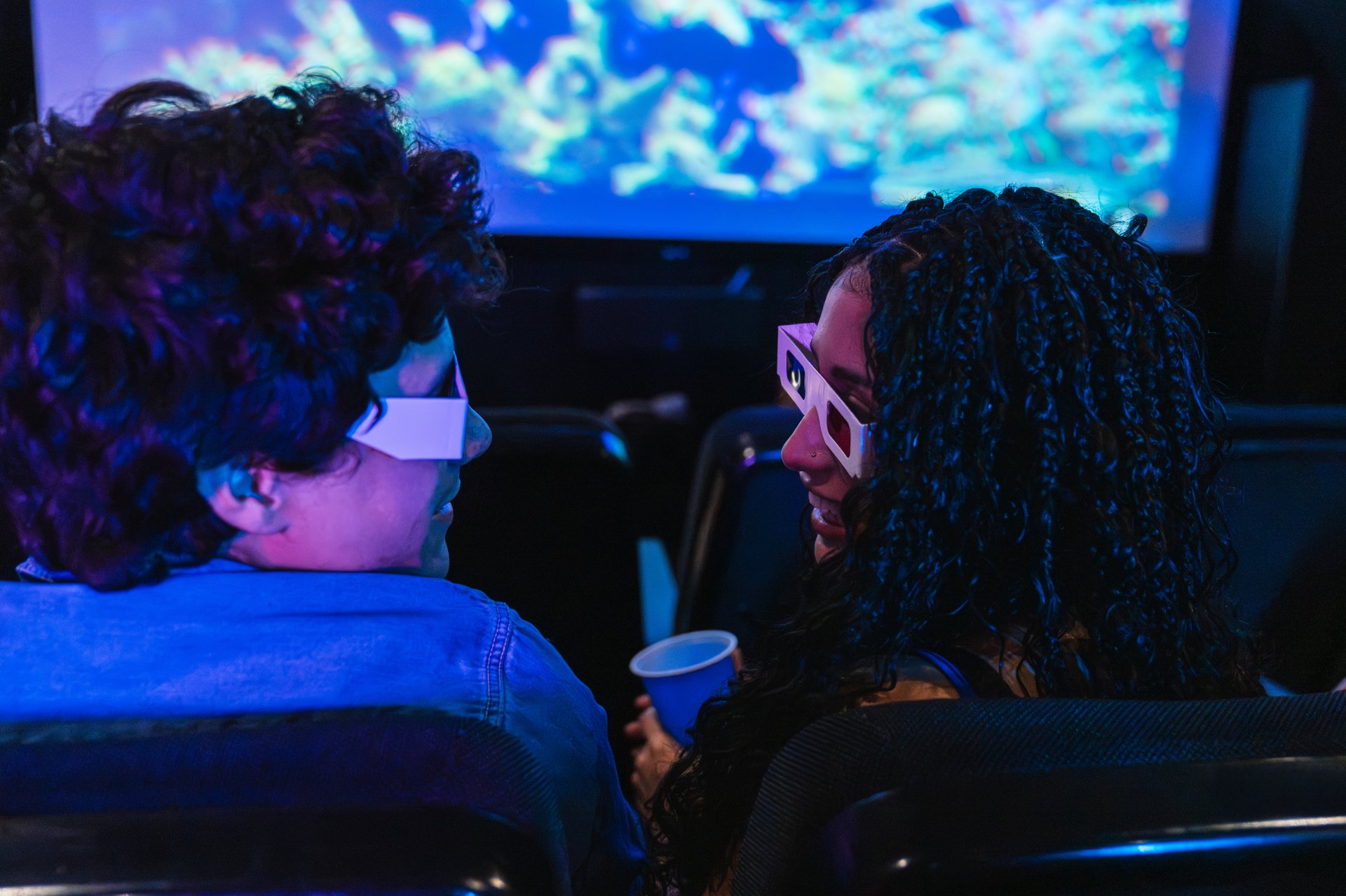 Young couple enjoying a 3d movie at the cinema, wearing 3d glasses and sharing a moment together