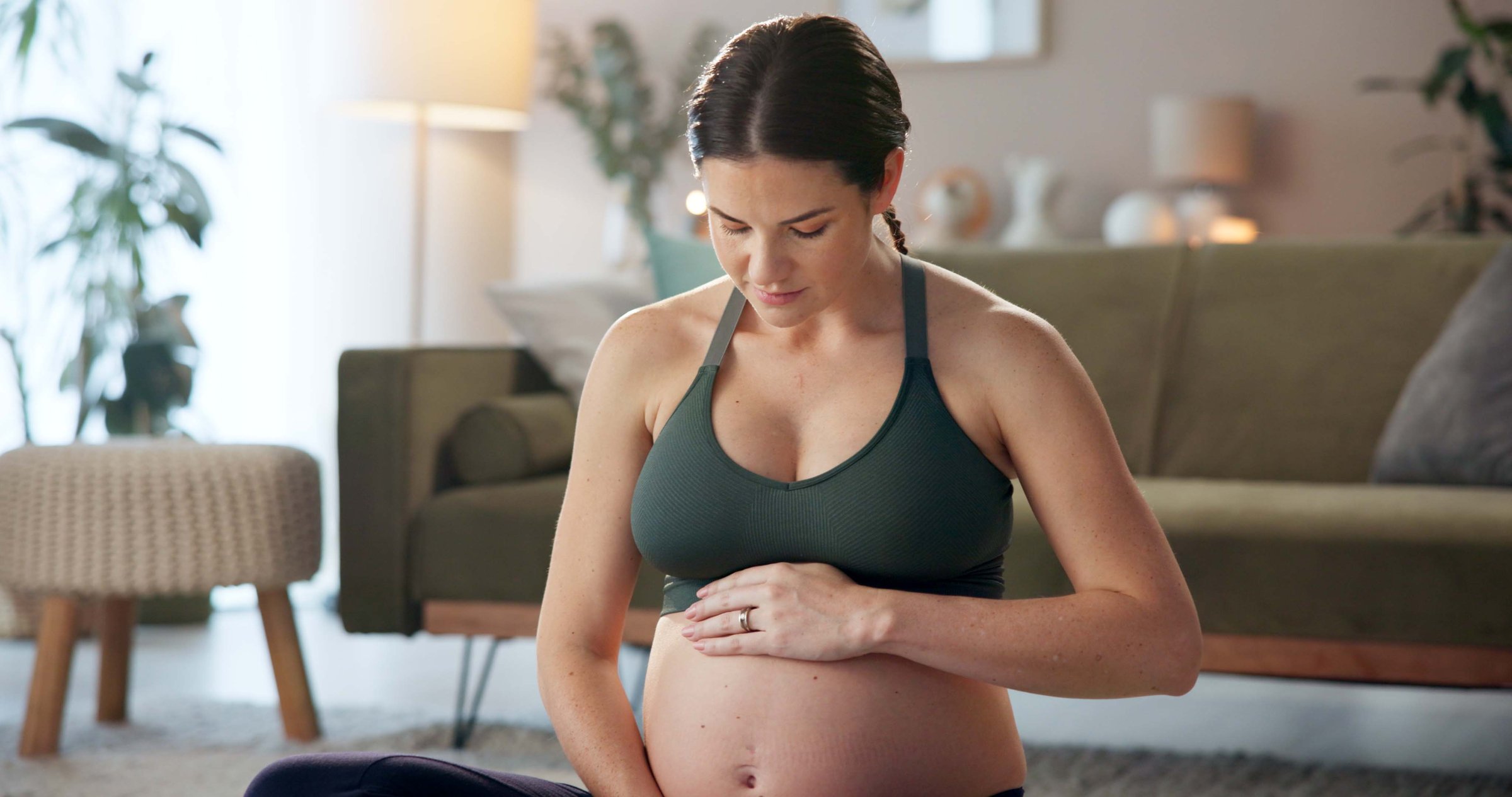 Pregnant woman, exercise and stomach on floor in home with thinking, care and wellness in living room. Person, mother and reflection with touch, love and prenatal growth for belly in lounge at house