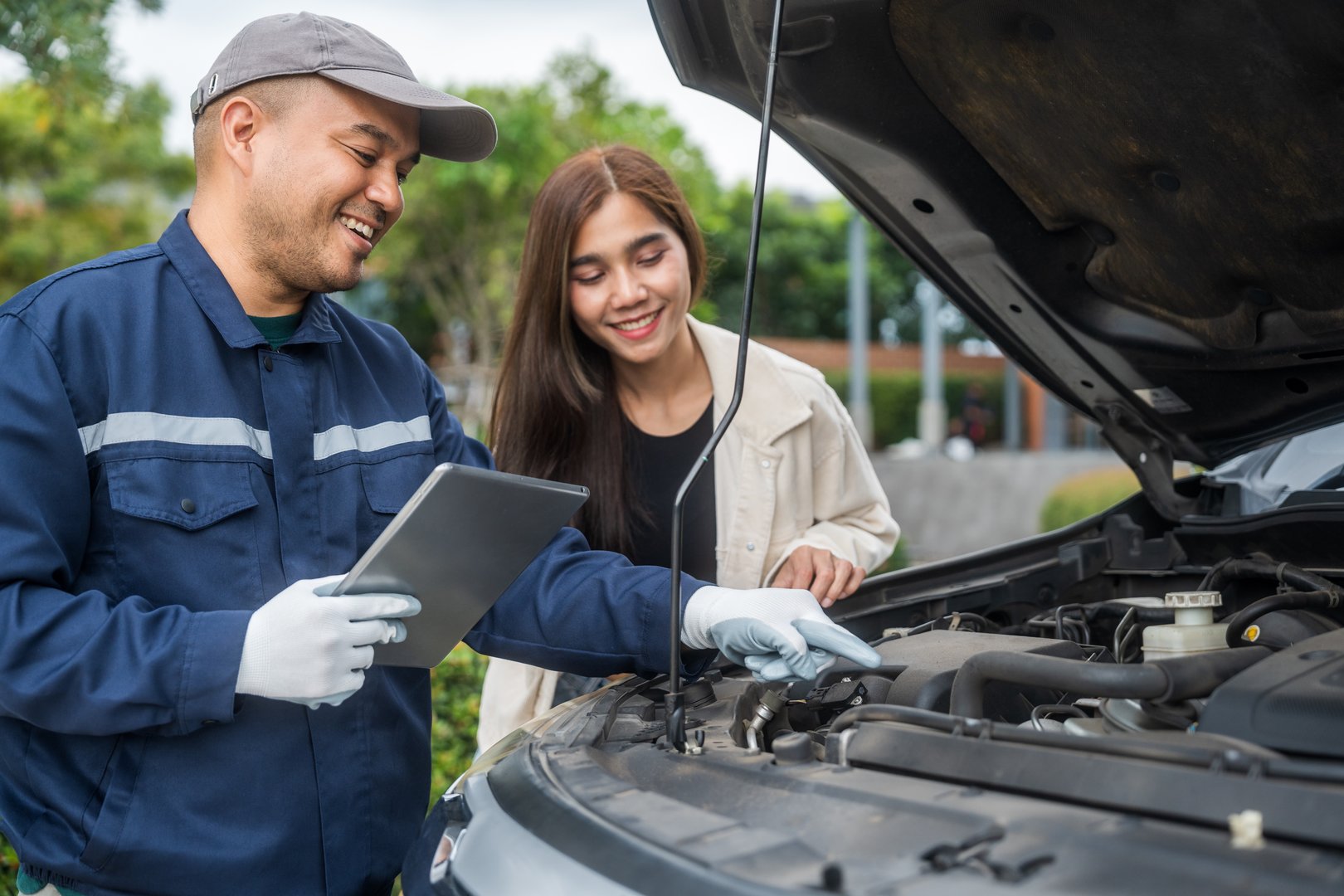Young female driver call Auto mechanic car service. Broken Down car outside the road help and support customer. Discussing repairs problems to vehicle.