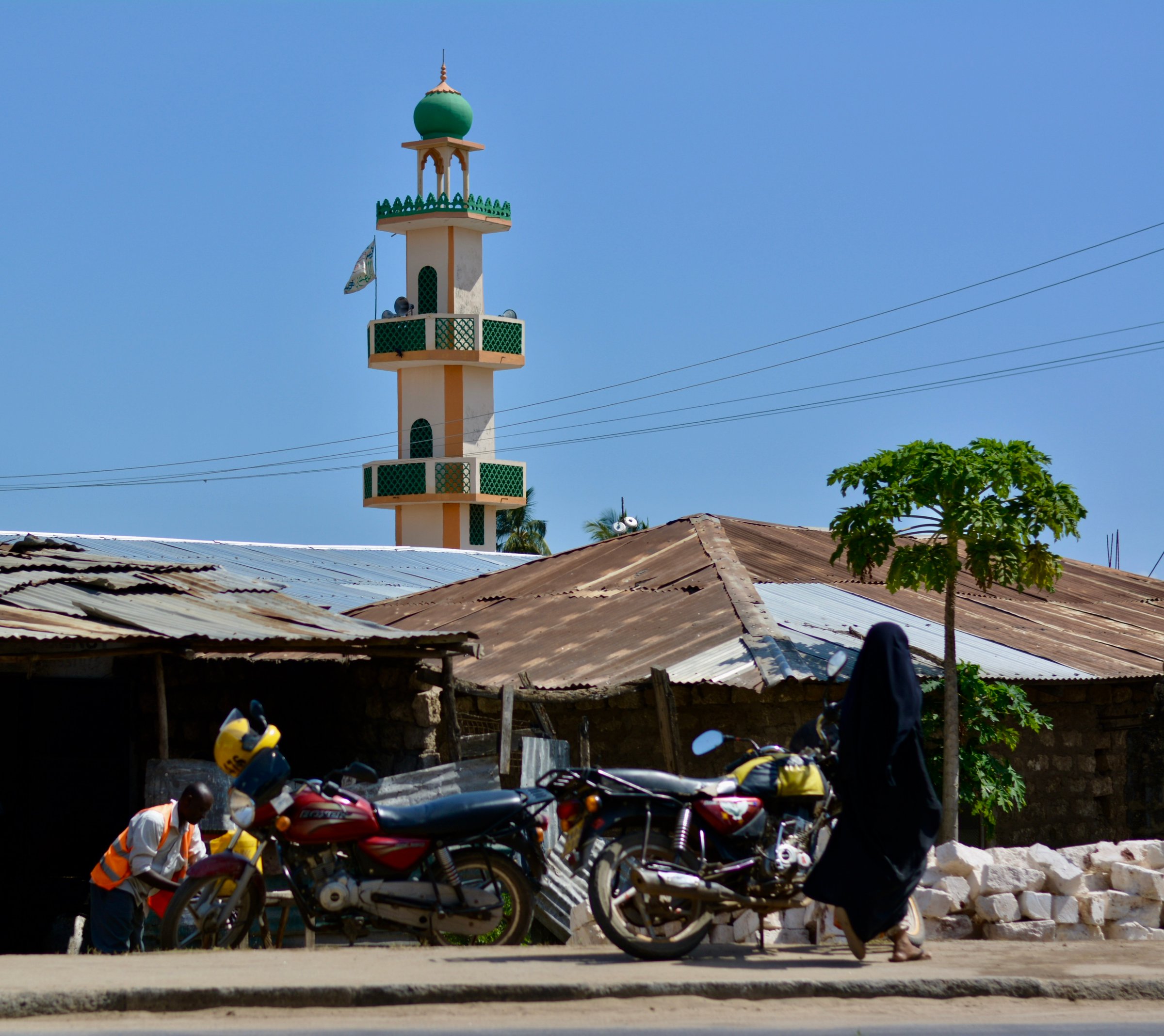 Coastal town in Kenya. Malindi. Muslim woman walking on the streets. Mosque at the back.