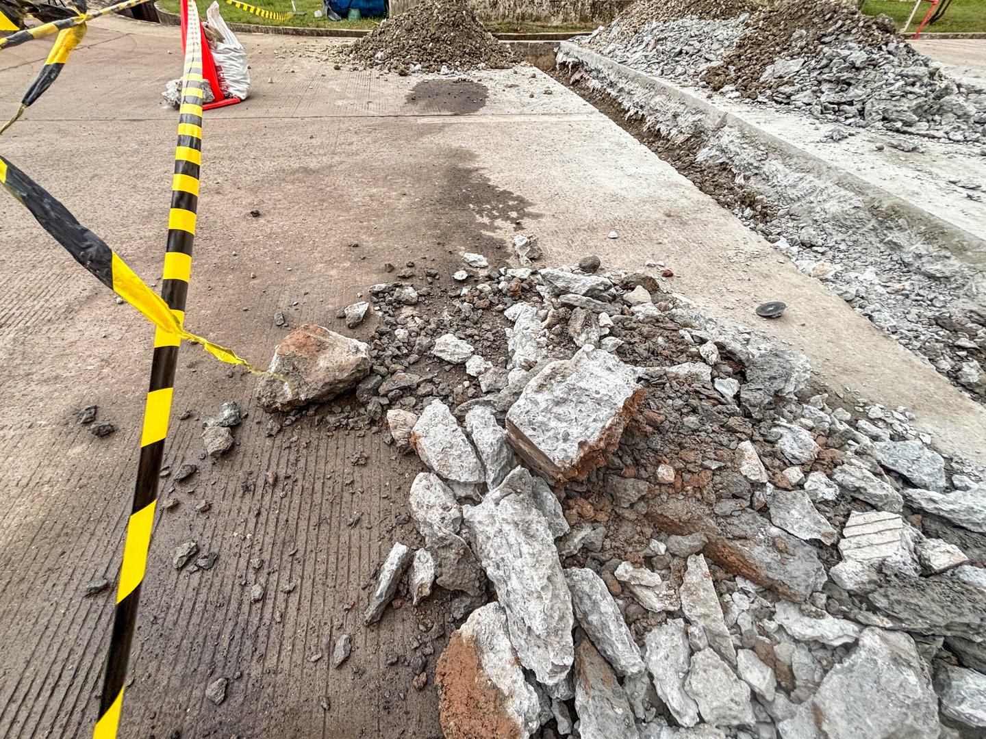 Demolition site shows construction debris and caution tape on damaged surface outdoor area