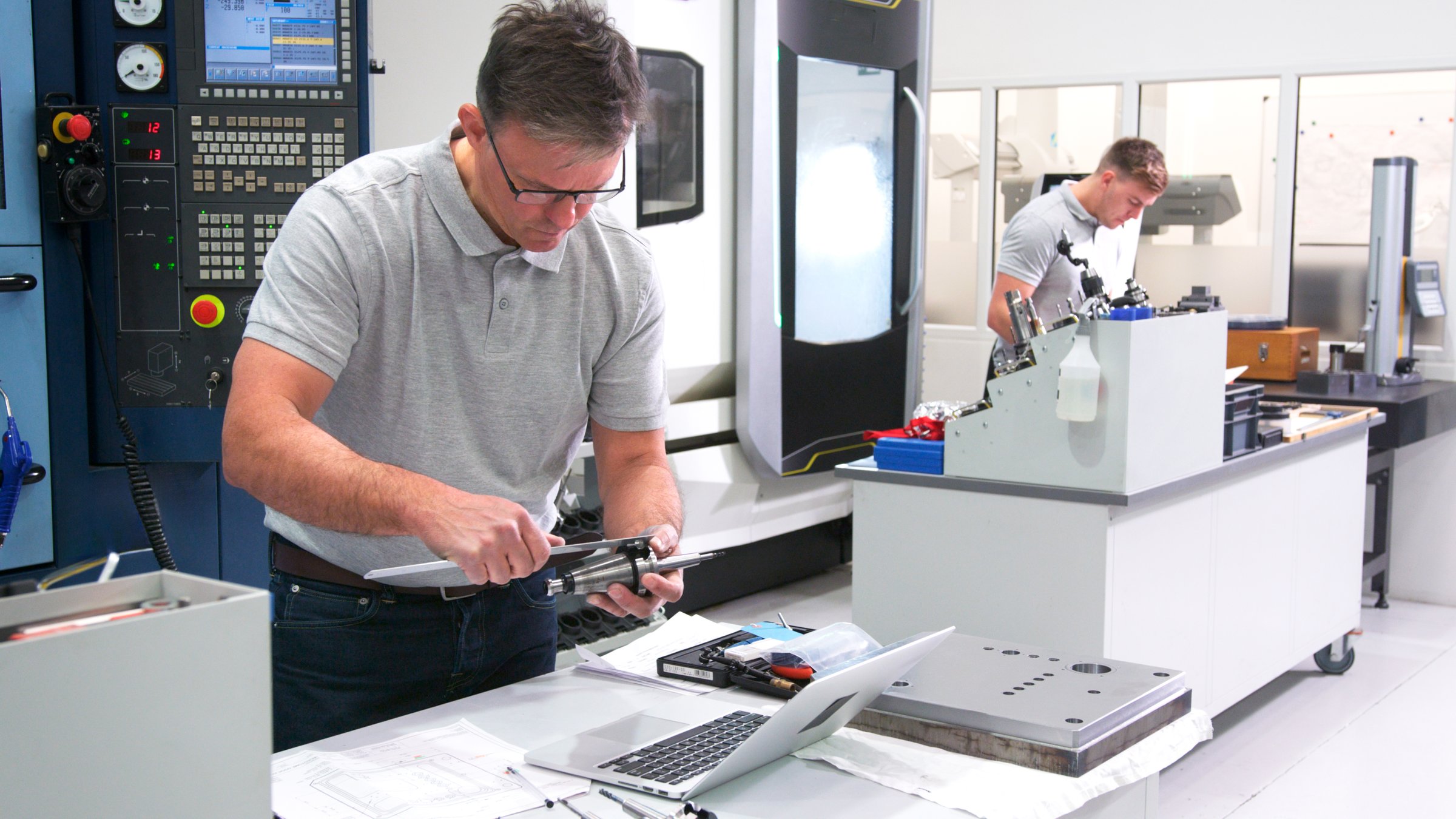 Mature Male Engineer In Factory Using CAD Programming Software On Laptop Measuring Component