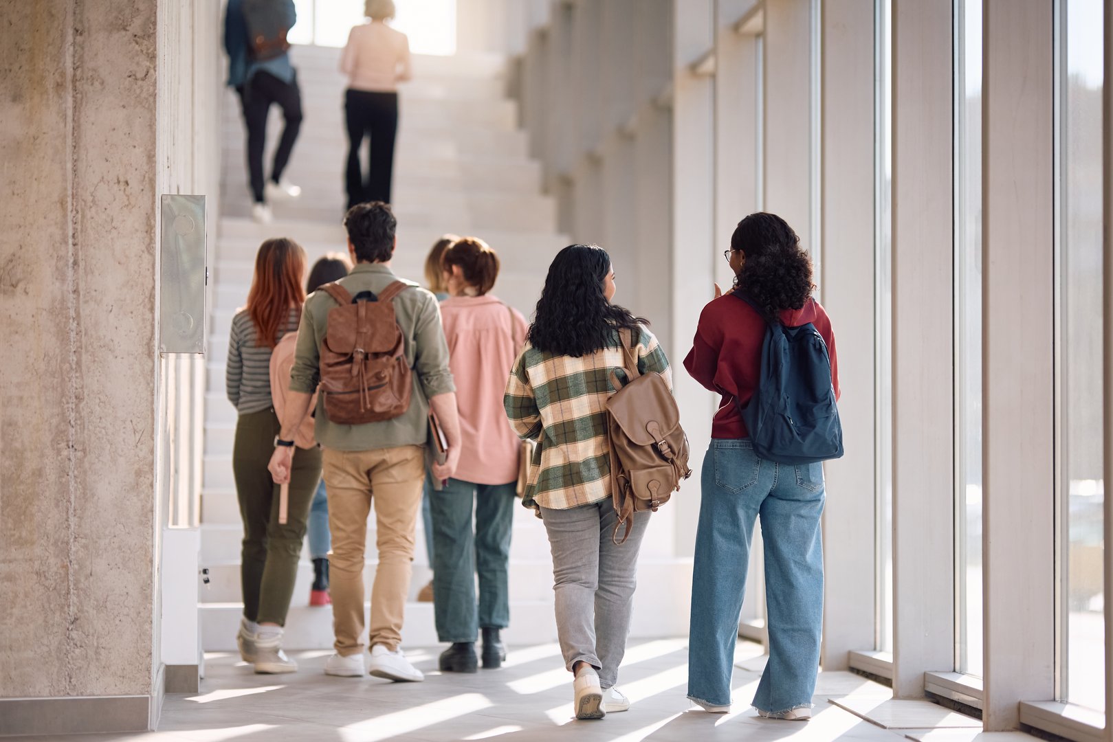 Back view of university students walking through hallway while going on a lecture. Copy space.