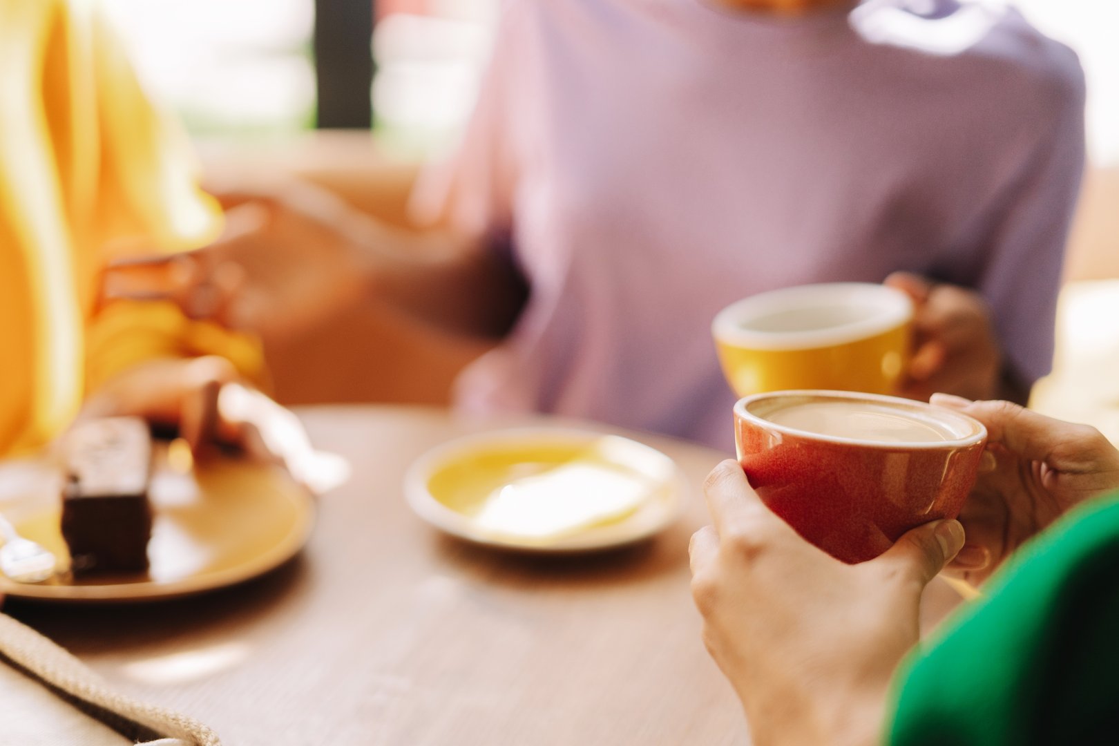 Women talking and enjoying coffee and cake in cafe selective focus, closeup. Coffee break concept