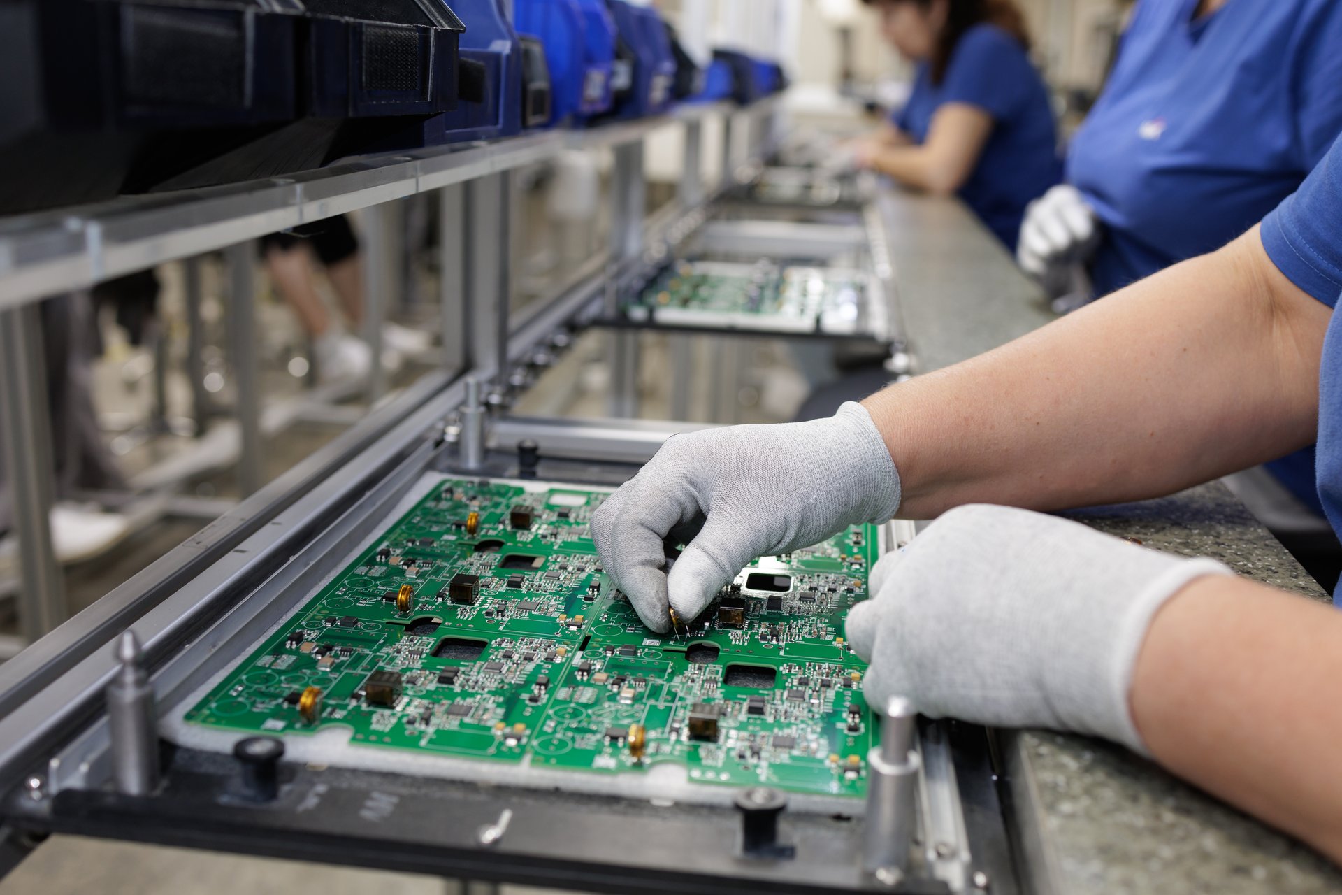 Operator places components on a printed circuit board at an ESD workstation on a modern electronics production line in factory