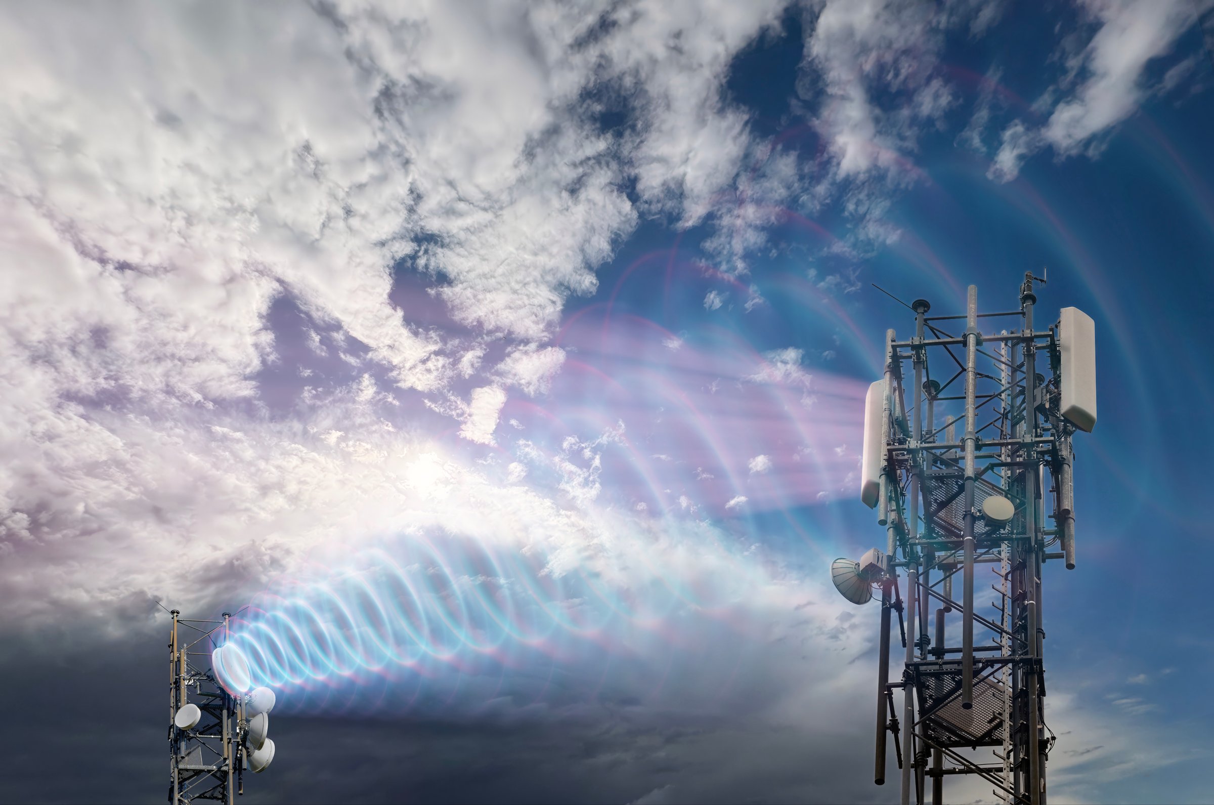 Cellular antenna sends radiation to another antenna. Mobile communication, global network, data transfer under a cloudy sky.