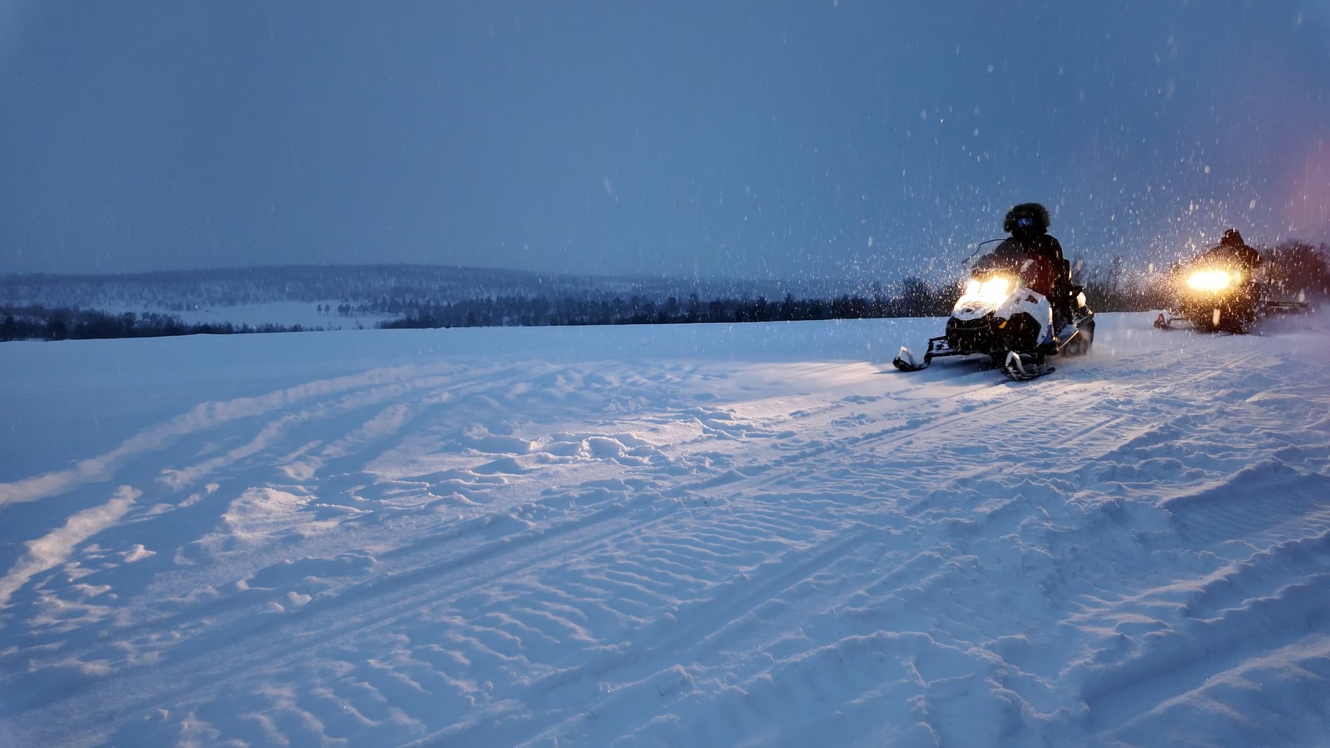 People operating snowmobile on rural countryside road in the winter.