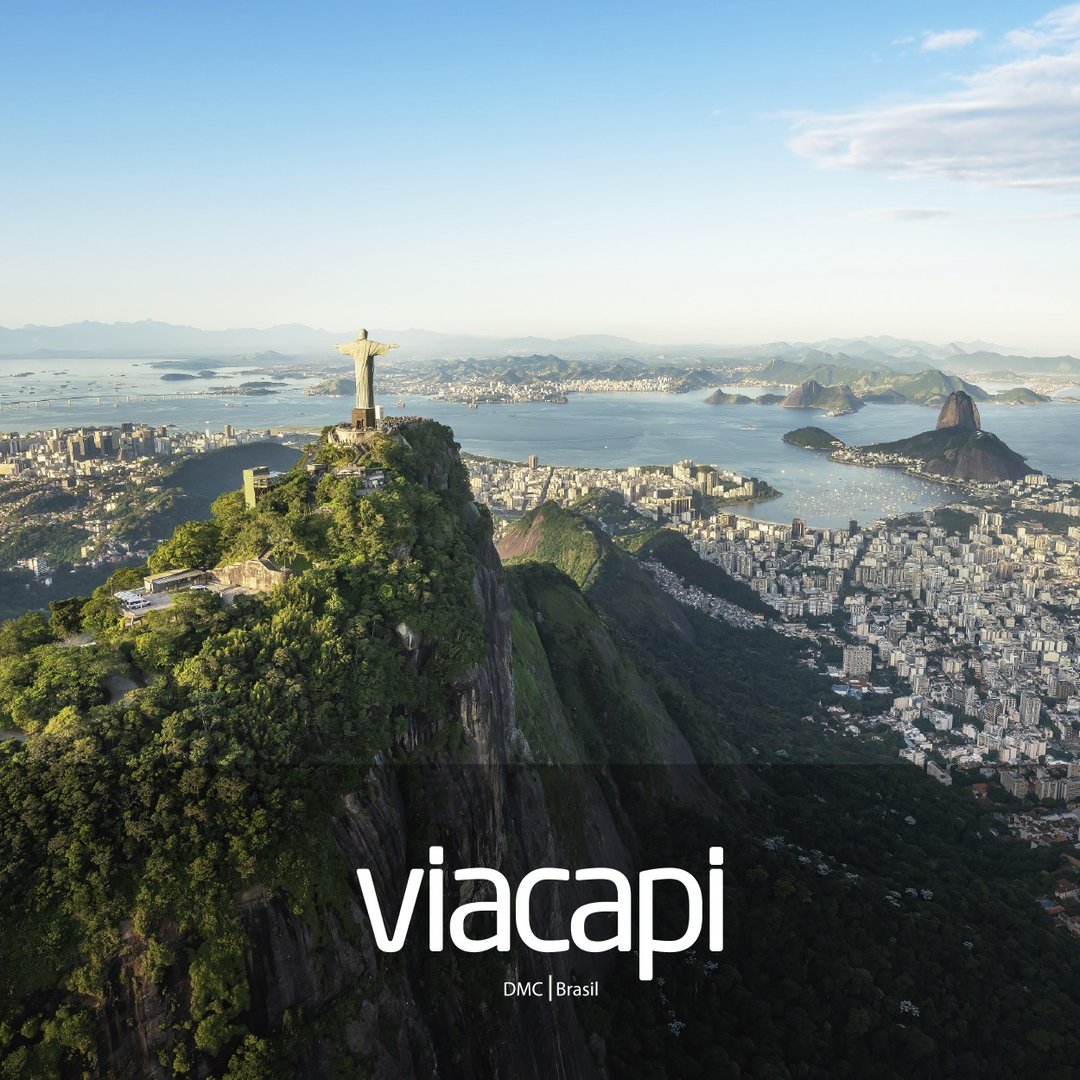 Aerial view of Rio de Janeiro with Christ the Redeemer statue, surrounding cityscape, and mountains in the background.