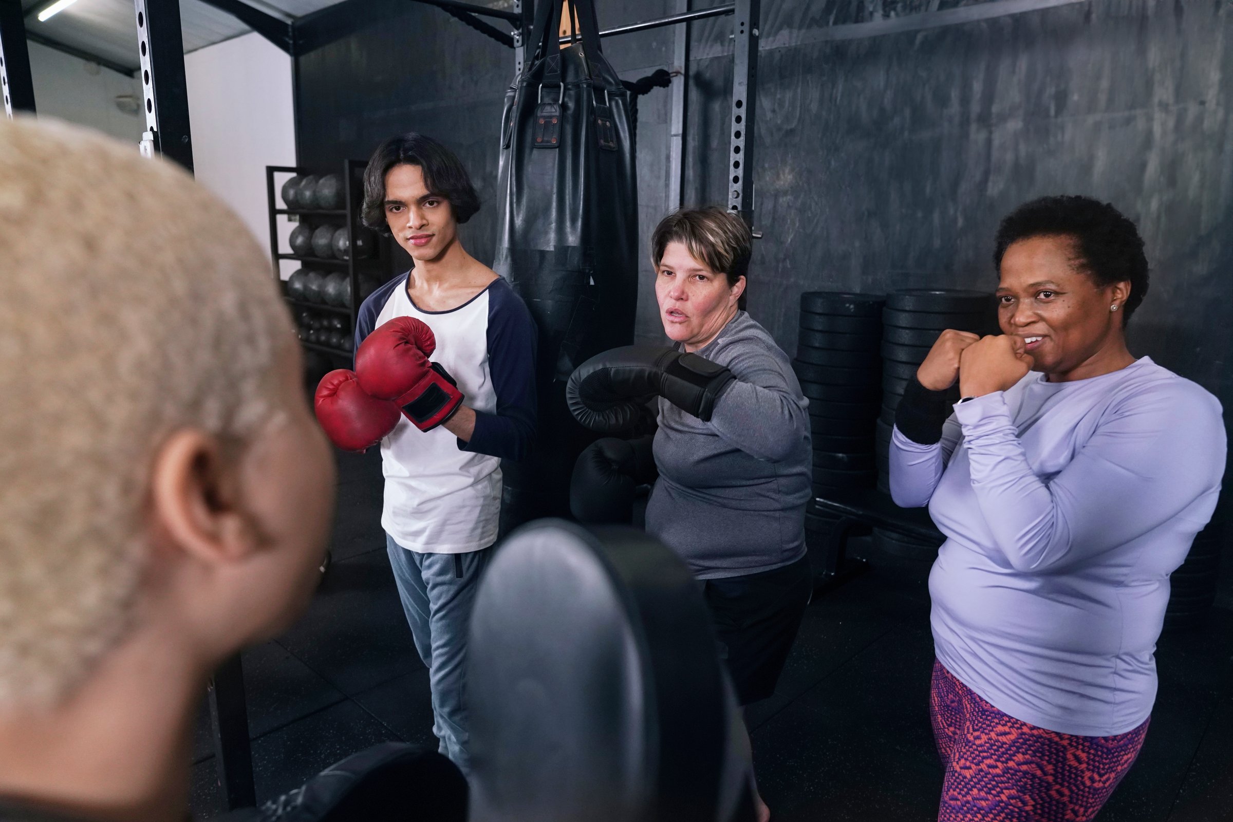 People practicing box in gym with instructor