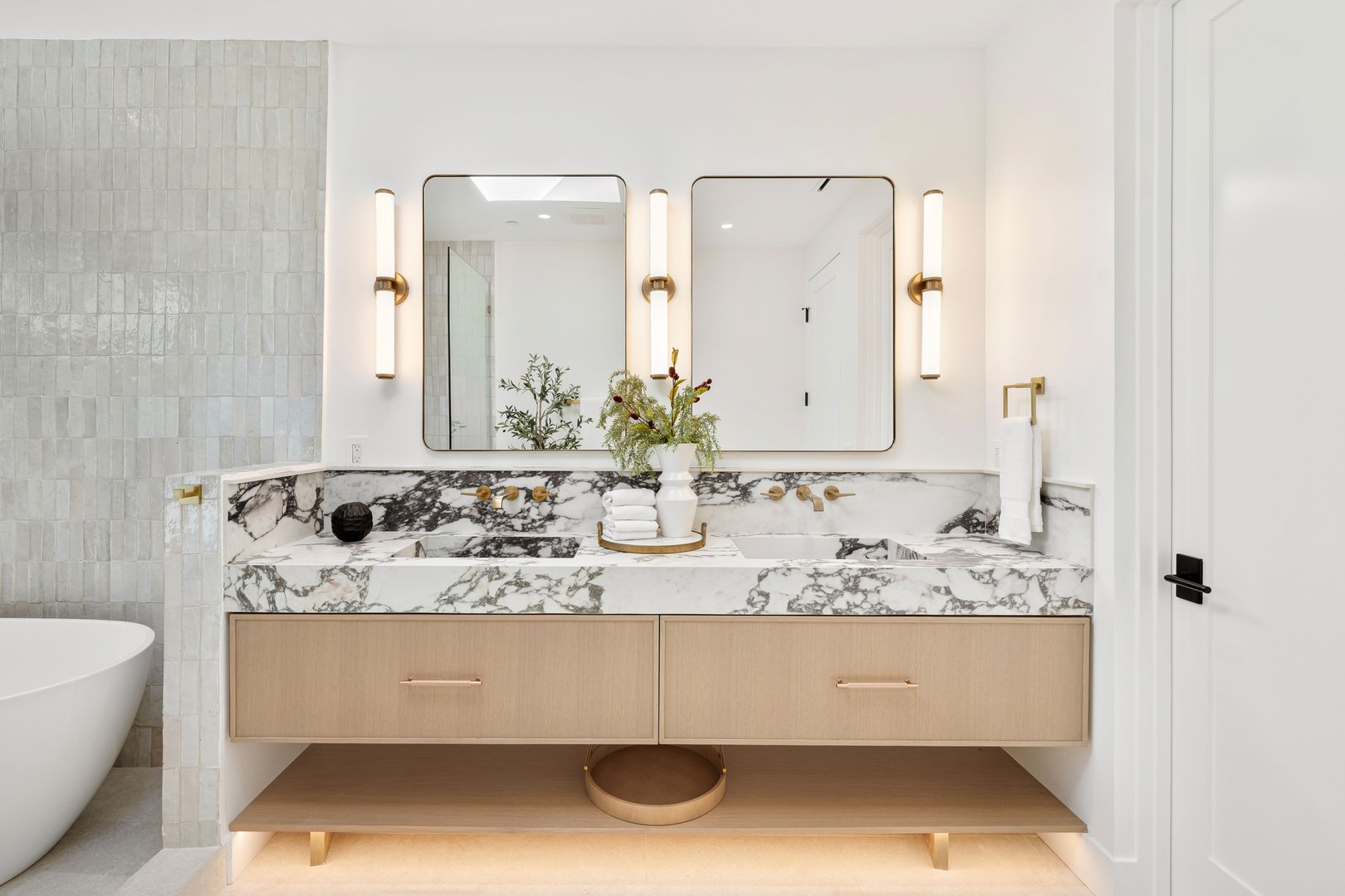 Modern bathroom with marble countertop, dual mirrors, and elegant lighting, featuring a stylish vanity and decorative accents.