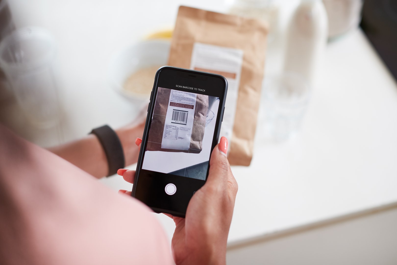 Woman Wearing Fitness Clothing Scanning QR Code On Food Packaging To Find Nutritional Information