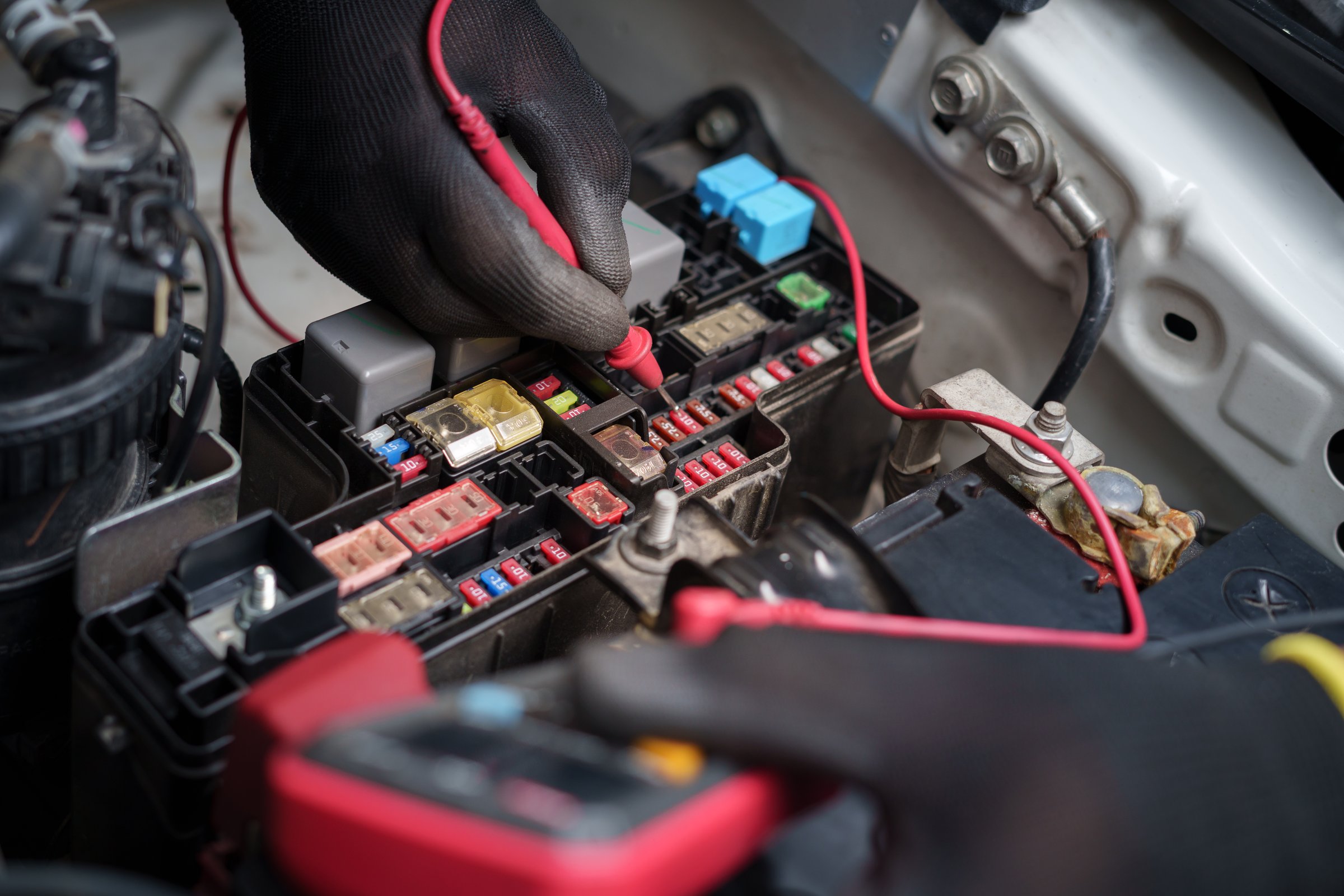 Car Fuse Box Electrical Testing with Multimeter.Technician Checking Automotive Fuses.