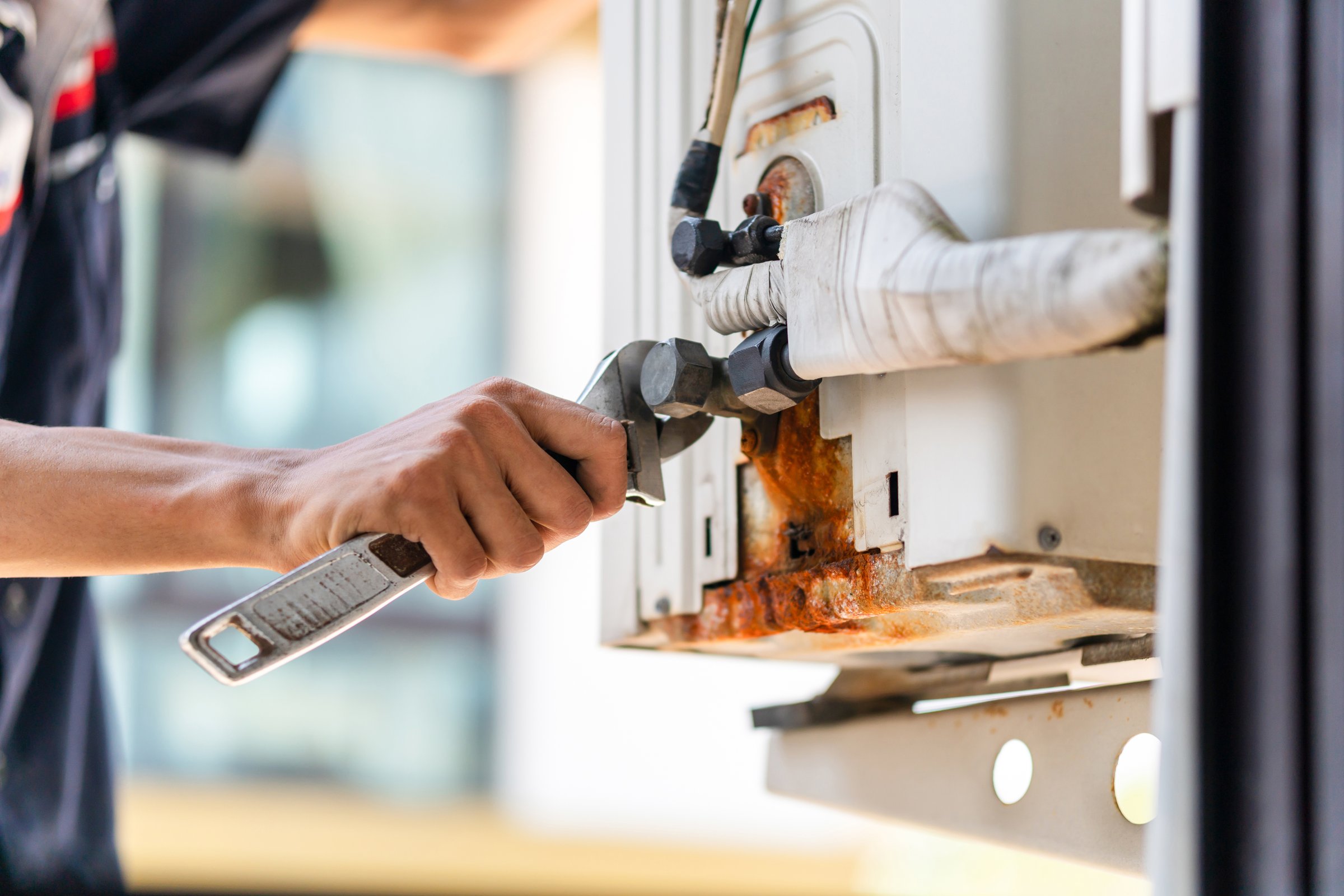 Close-up of Air Conditioning Repair, repairman with wrench fixing air conditioning system