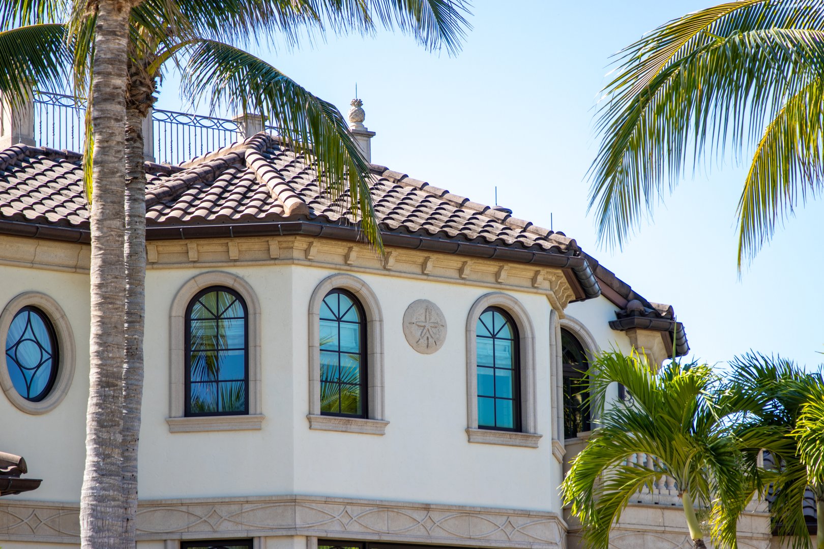 A Spanish style house design in a tropical location with palm trees.