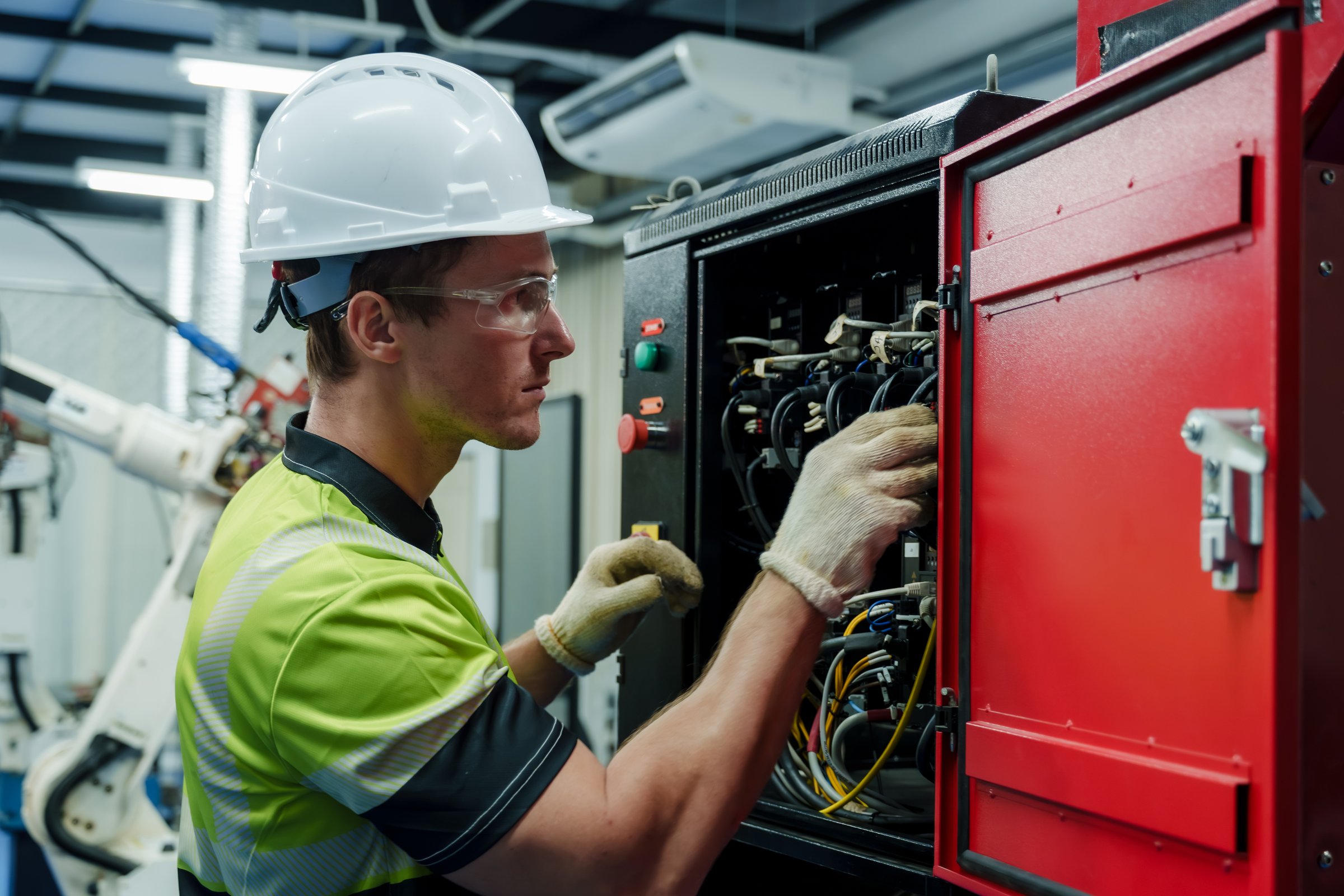 engineer performing electrical inspection and maintenance on industrial control cabinet during smart factory automation operation ensuring system stability and safety standards