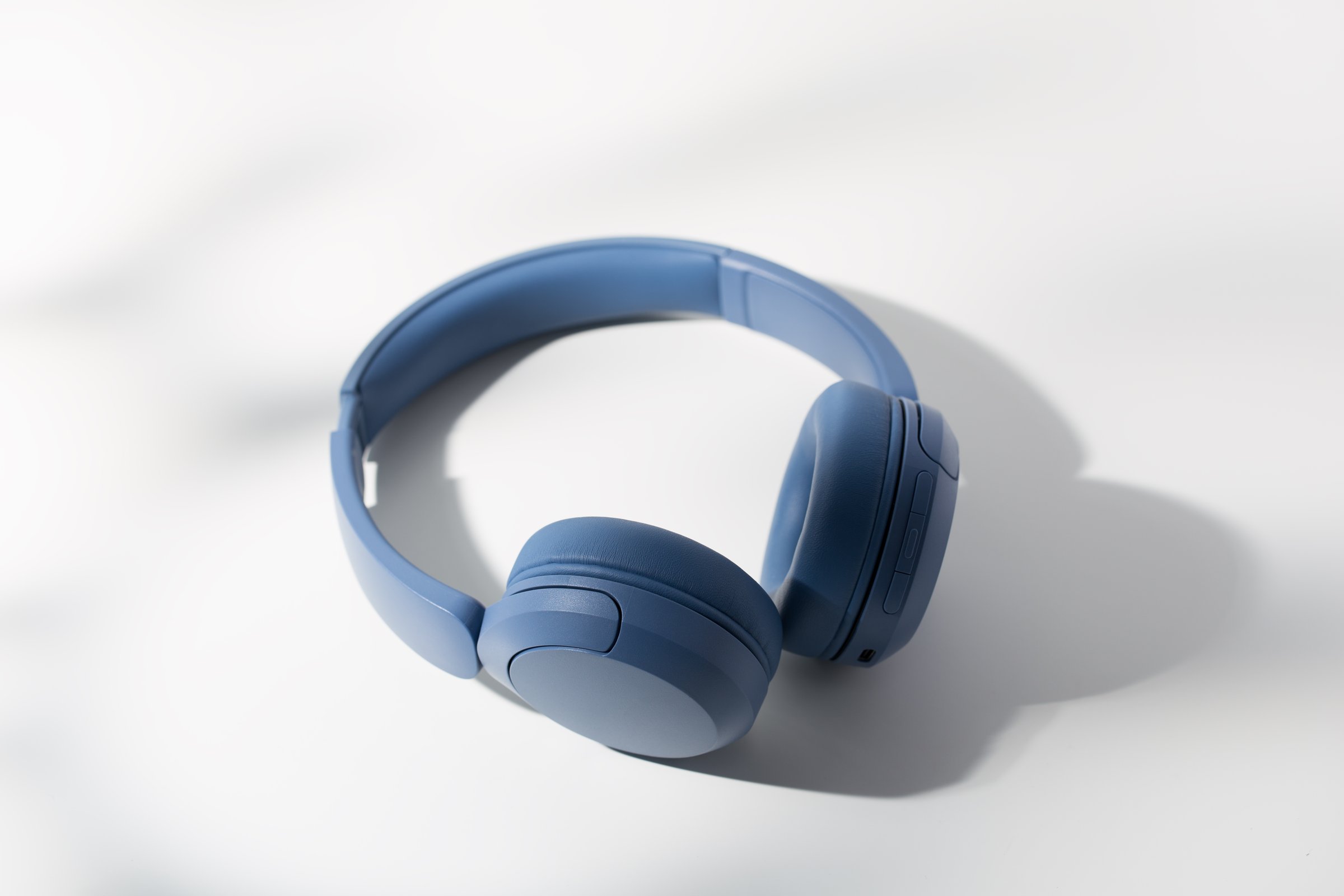 Modern blue headphones rest on uncluttered white backdrop.