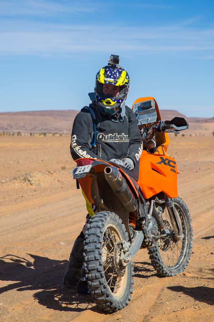 Merzouga, Morocco - February 26 2016: Person next to a motobike with action cam fixed on his helmet with the wide desert of Morocco in the backround on a sunny day.