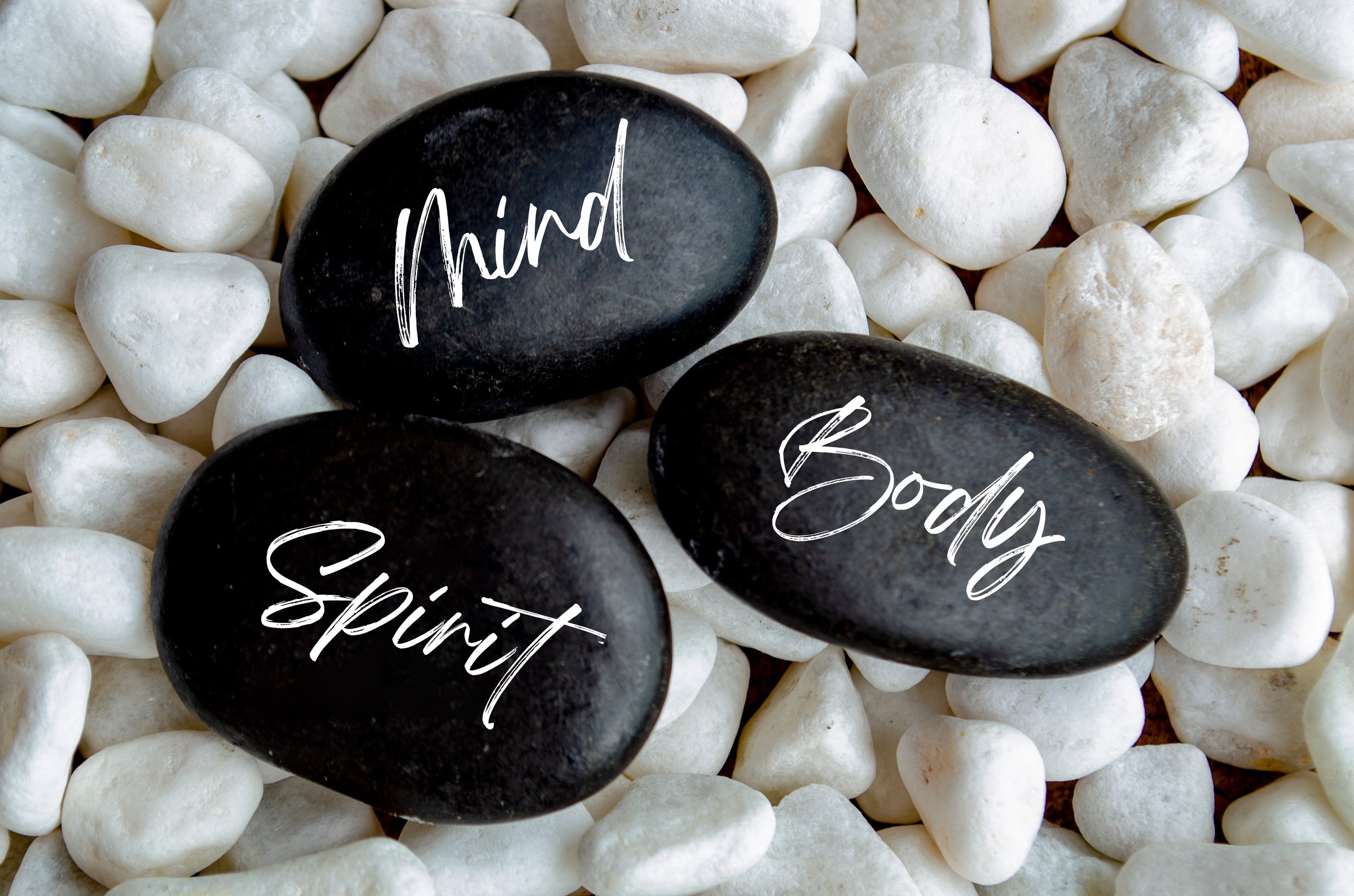 Top view of mind, body spirit text on black zen stones.