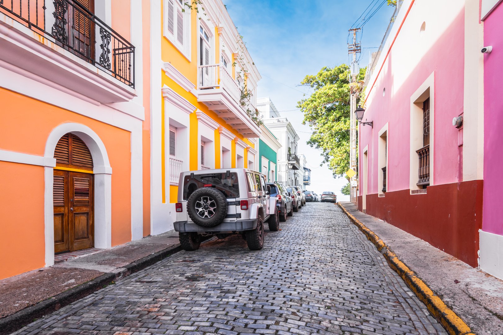Travel image with colorful buildings along a cobblestone street in old city center of San Juan, Puerto Rico. Diminishing perspective. Vibrant colors.