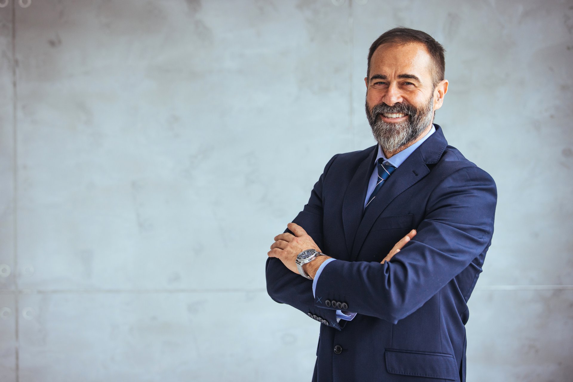 Portrait of a confident mature businessman working in a modern office. Mature cheerful executive businessman at workspace office. Portrait of smiling ceo at modern office workplace in suit