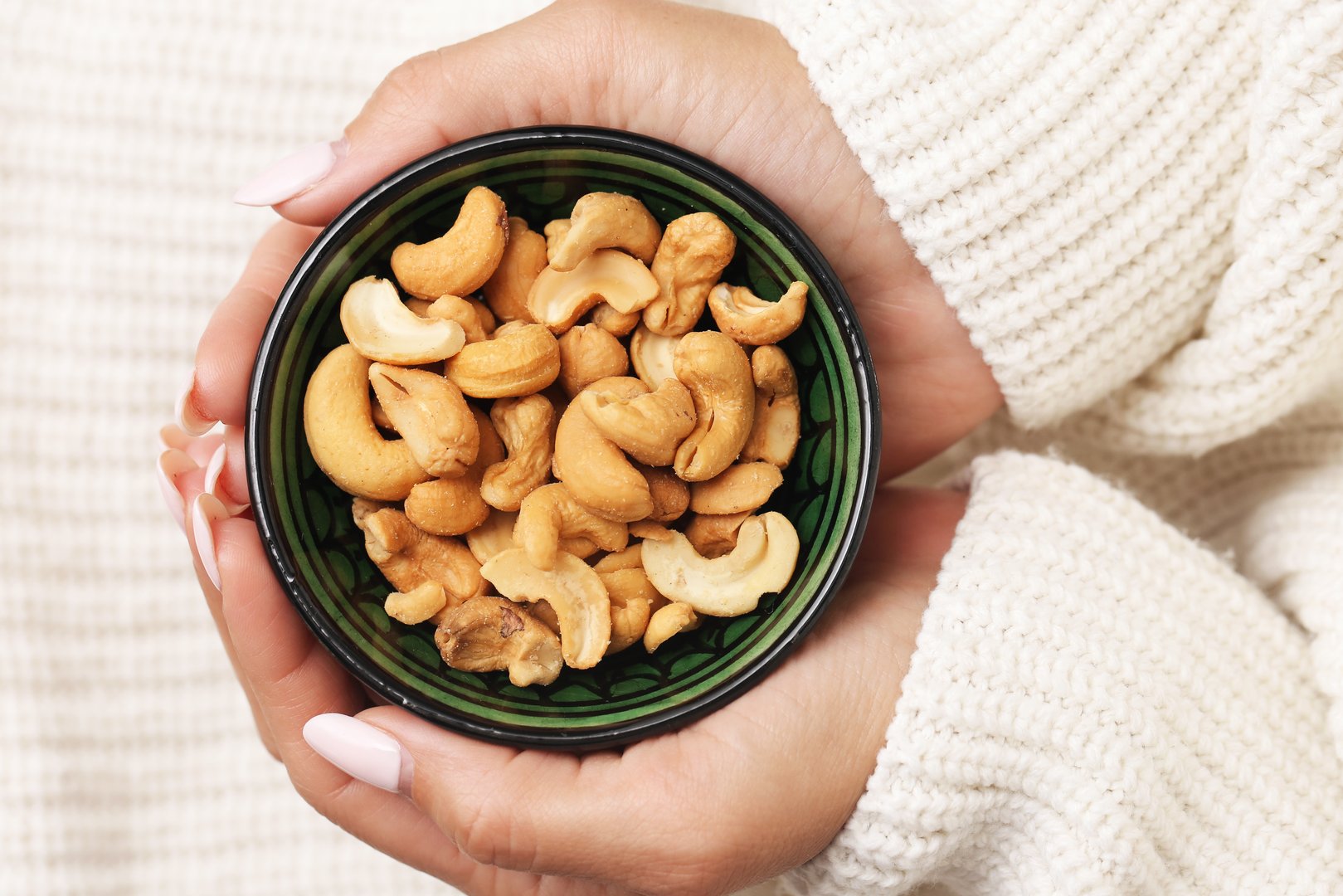 Vegan lifestyle and diet. Hand with cashews in bowl. Fresh organic nut mix.