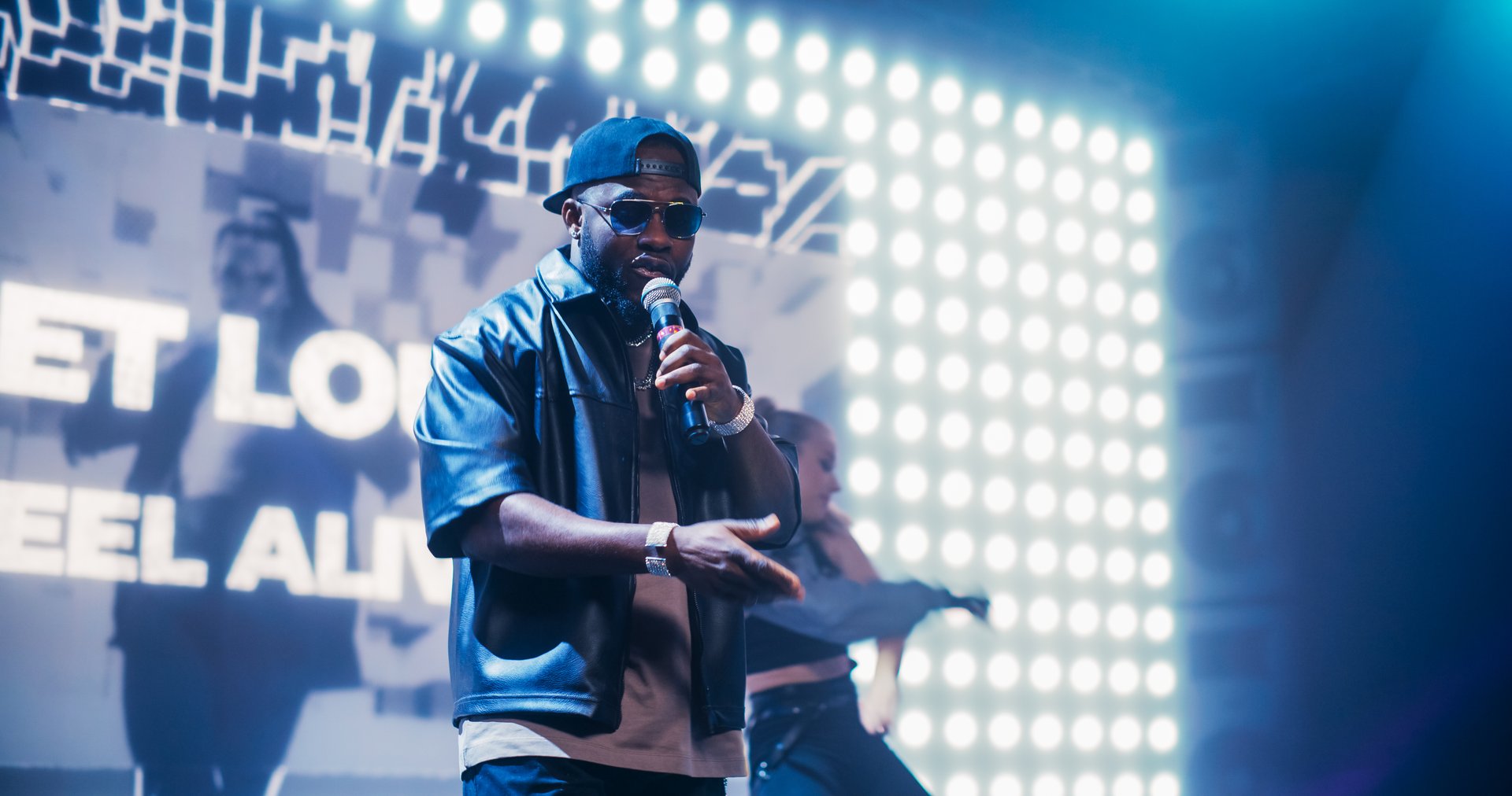 Rap Artist Performing on a Vibrant Stage with an Energetic Female Dancer, Entertaining a Large Audience in a Concert Hall. Performer Dancing a Hip Hop Choreography Routine in Smoke