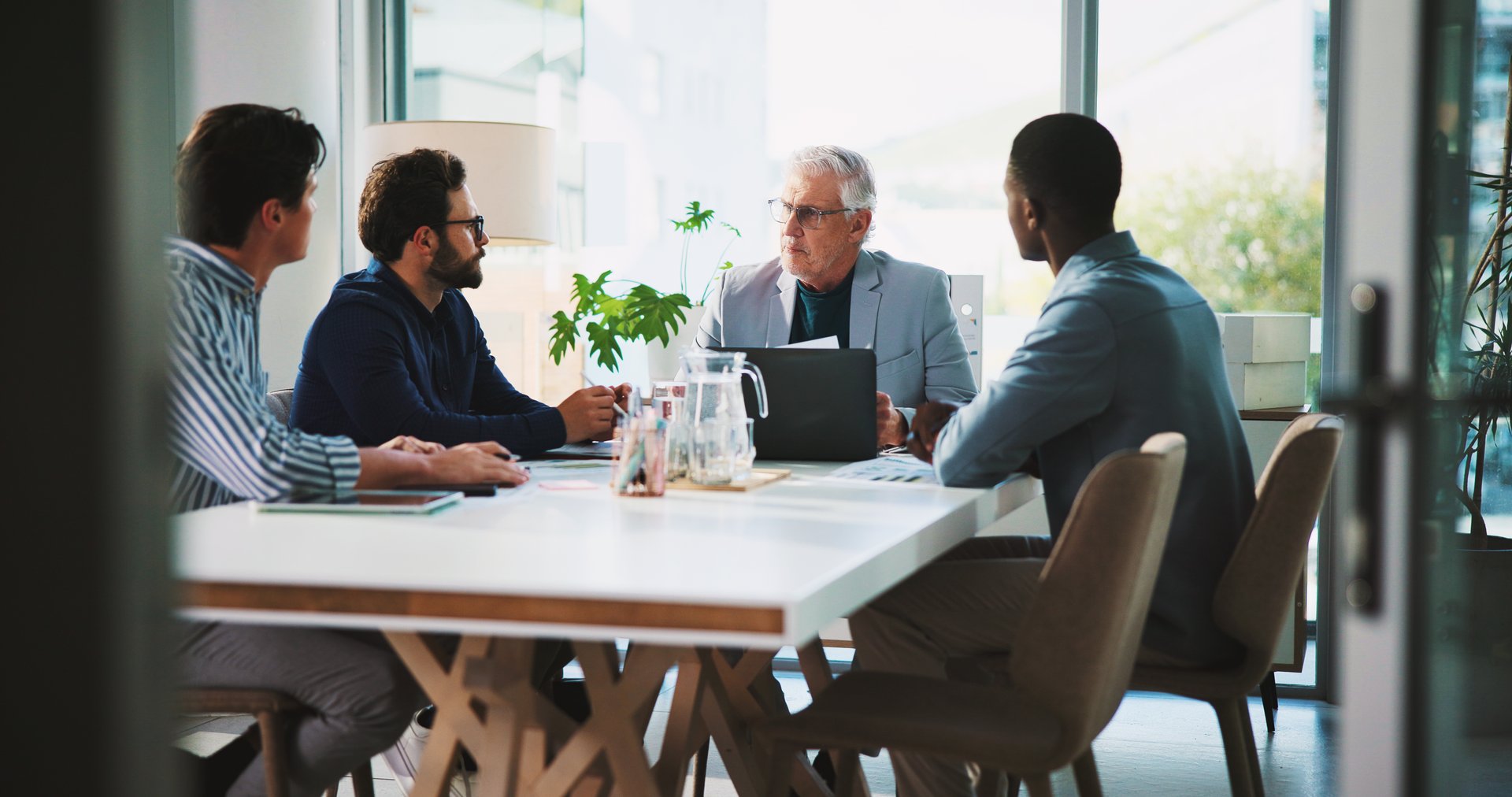 Boardroom, laptop and meeting with business people at table together for coaching or training. Computer, conversation and management with mentor teaching employee team in workplace for development