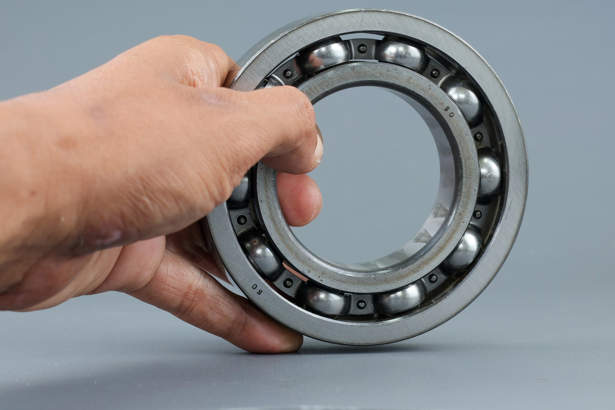 Hand holding Ball bearing isolated on dark background. Automotive spare part company. Heavy industry engineering company. Machine designing and manufacturing. Steel details for engineering mechanical.