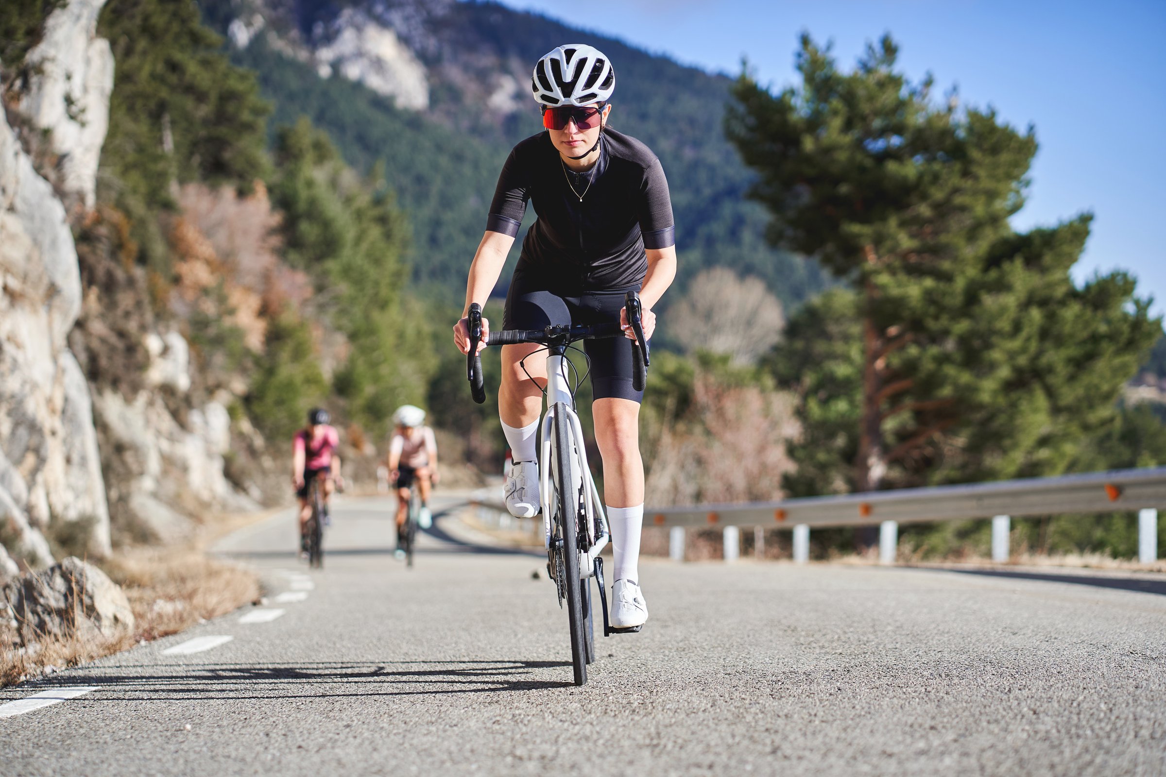 Focused female cyclist leading a group on a winding mountain road