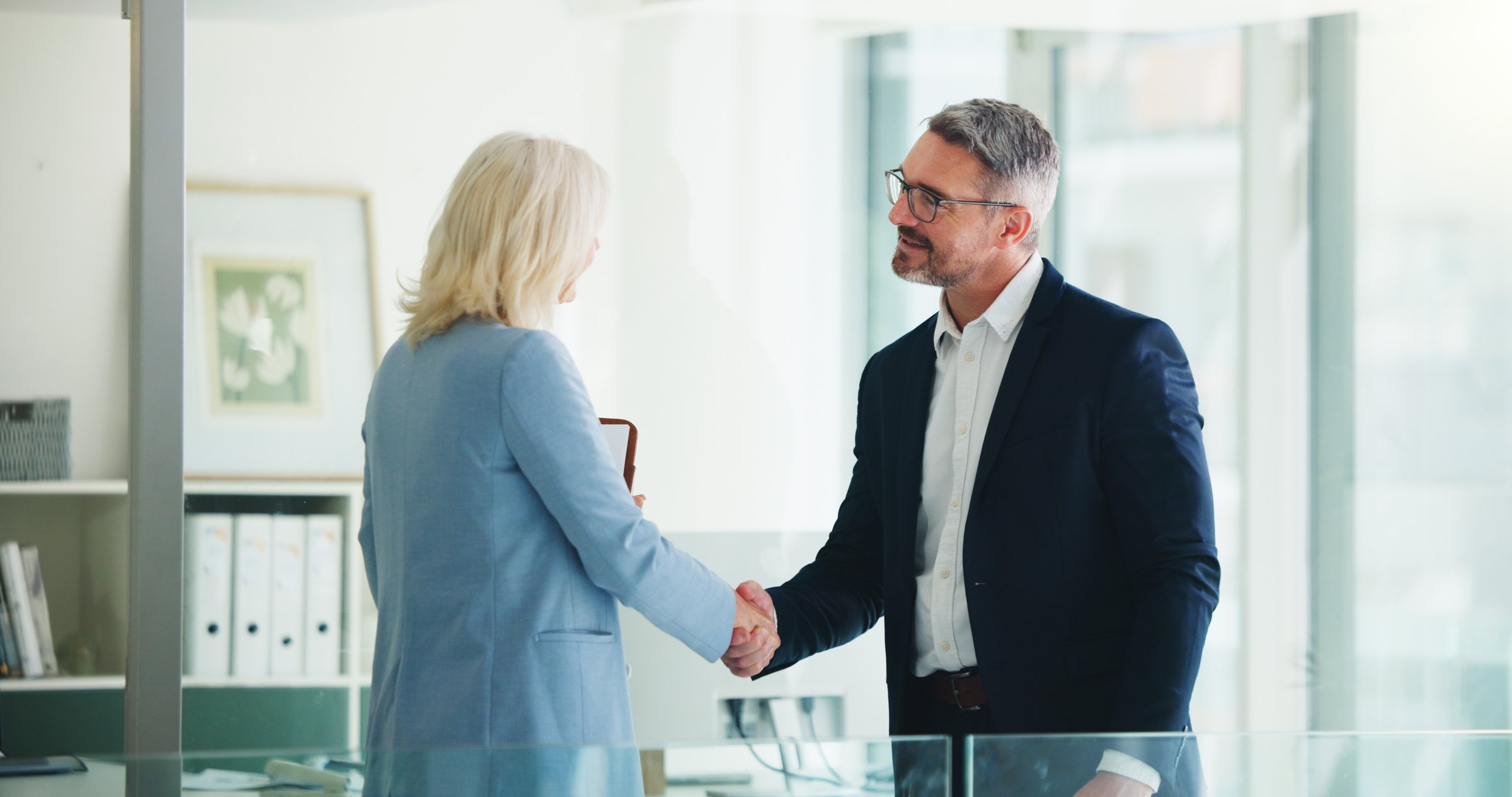 Handshake, partnership and business people in office with deal, finance contract or greeting. Welcome, negotiation and financial manager shaking hands with client for investment proposal in workplace