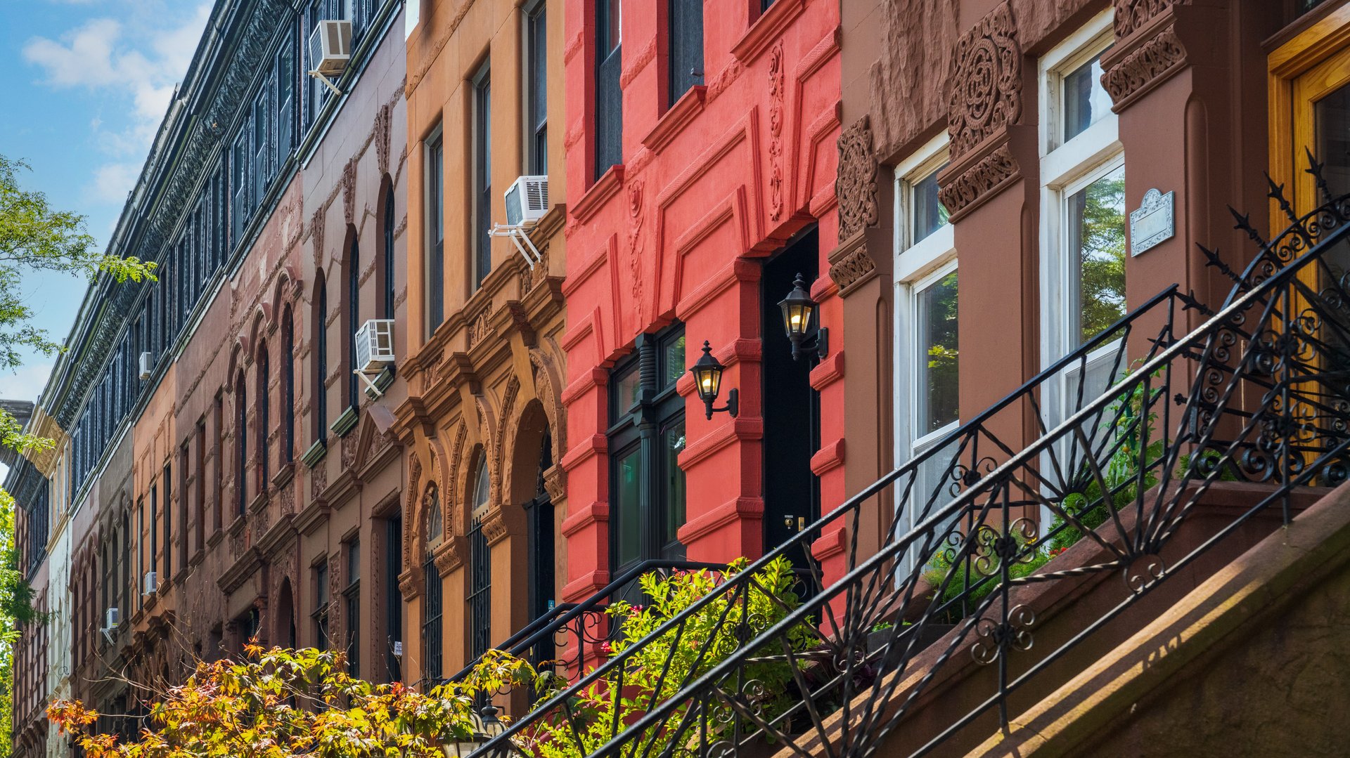 A row of colorful brownstone buildings with intricate architectural details in a city neighborhood.