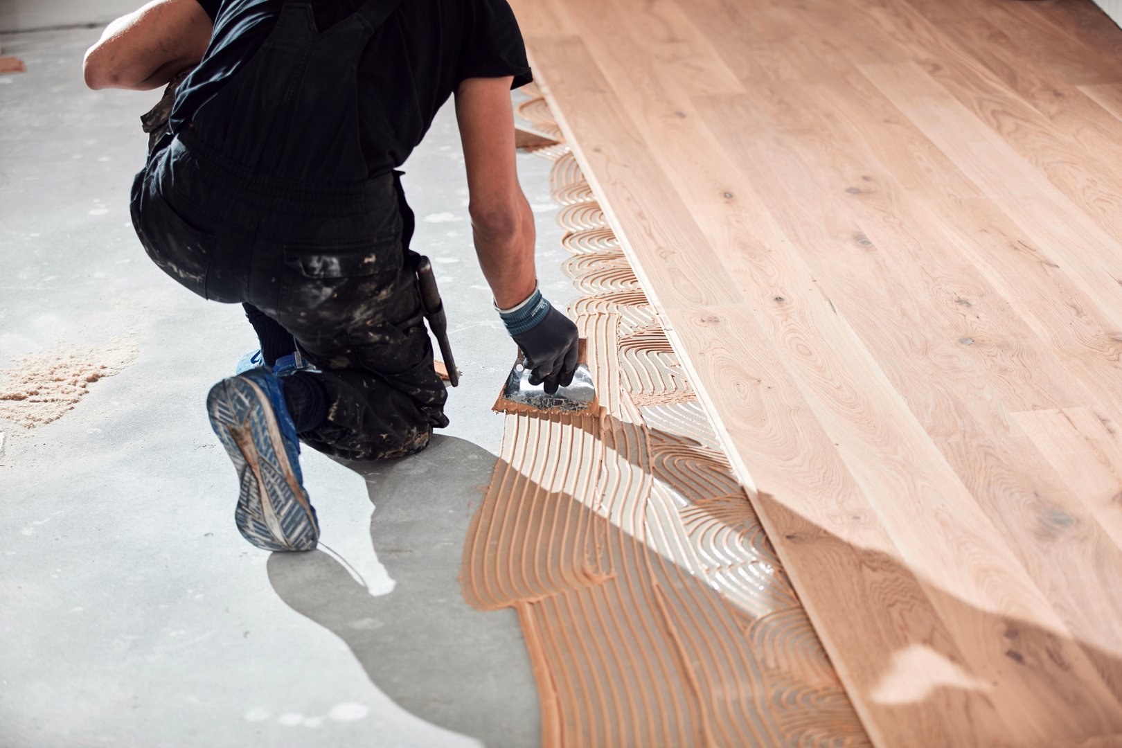 Professional handyman installing laminate flooring in a new apartment.